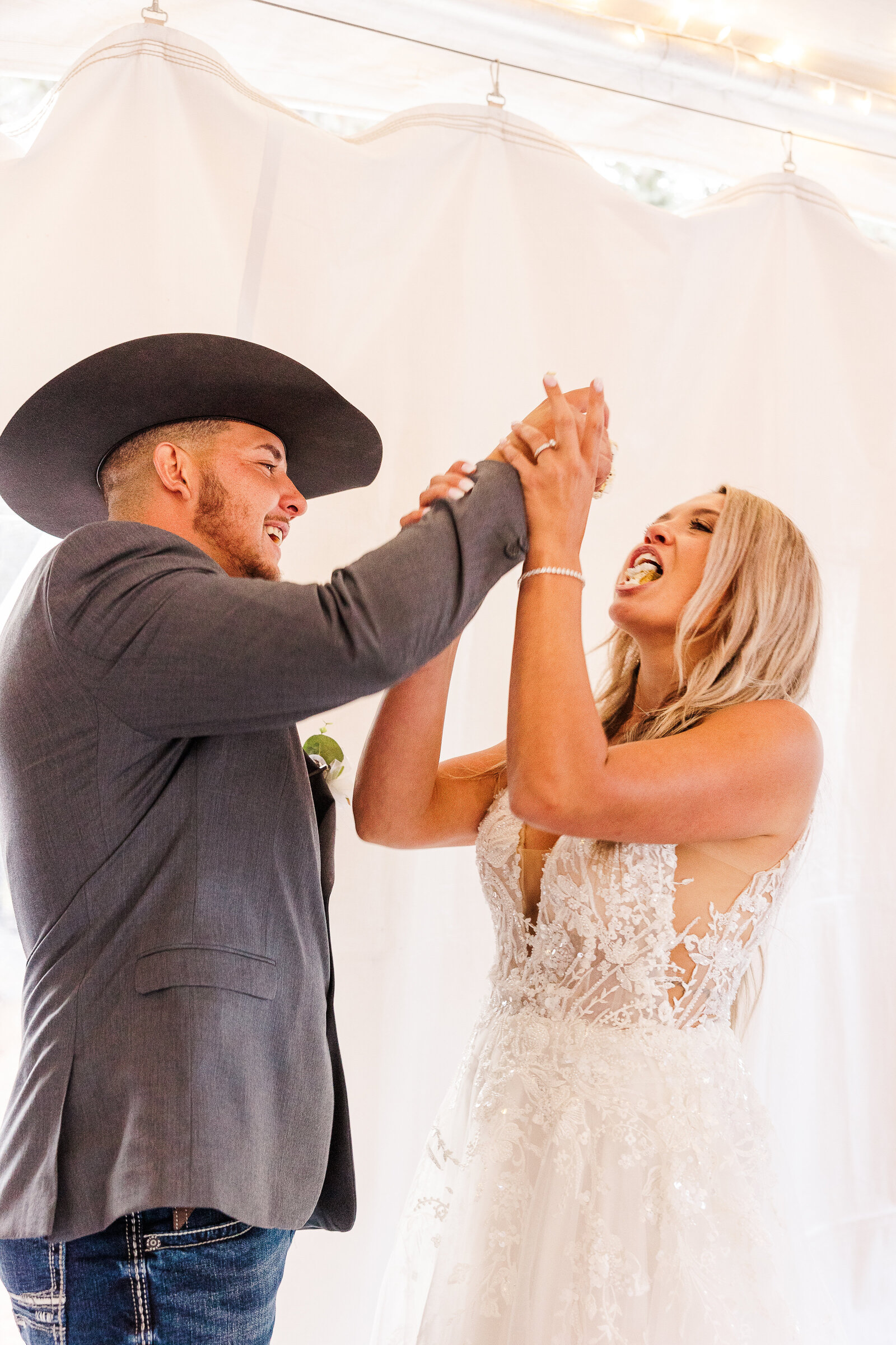 Bride and groom laugh as they feed each other a piece of their wedding cake at their Arrow Head Lodge Wedding - 