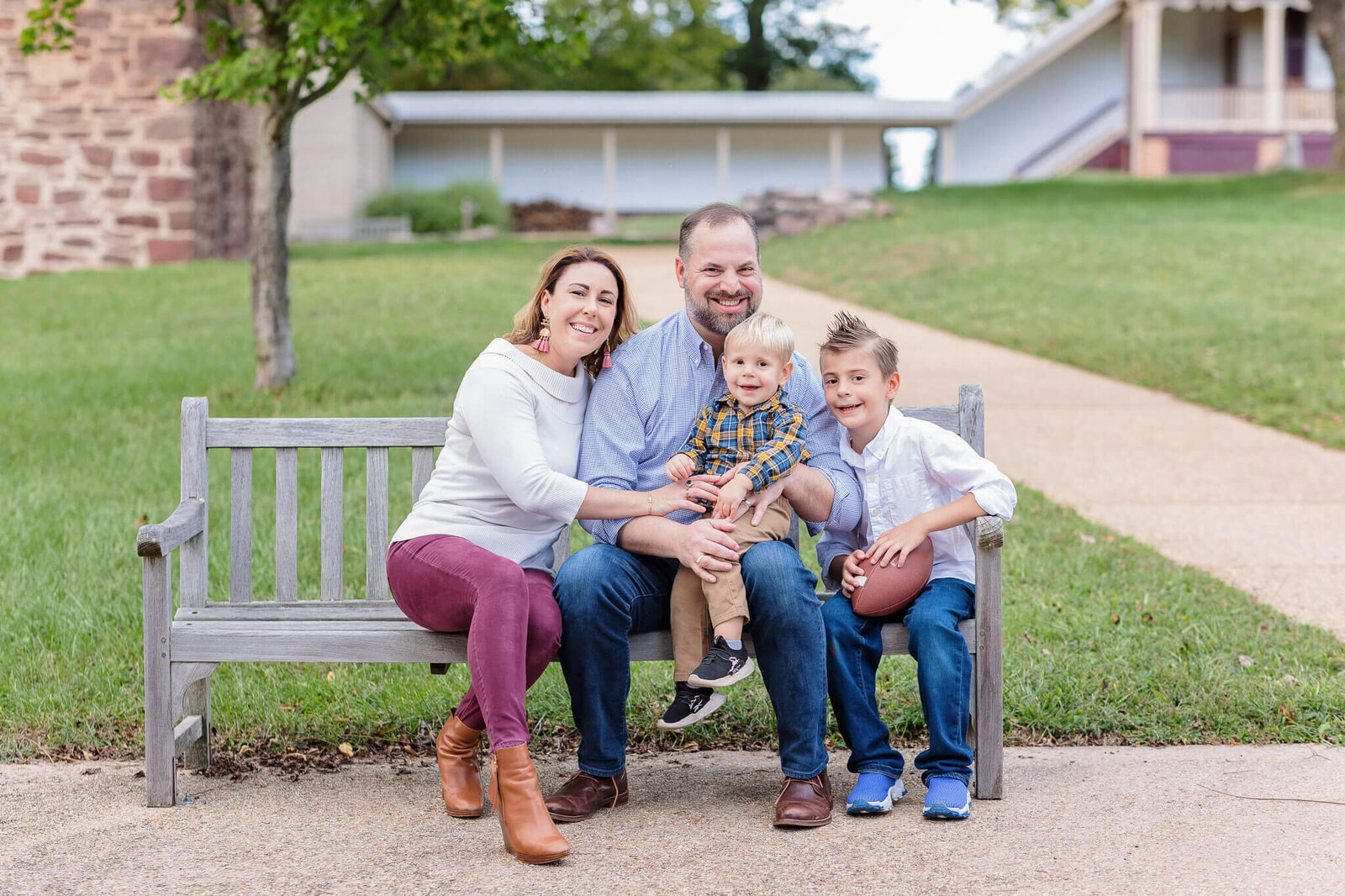 A NOVA family of four sitting on a bench at a park at sunset.