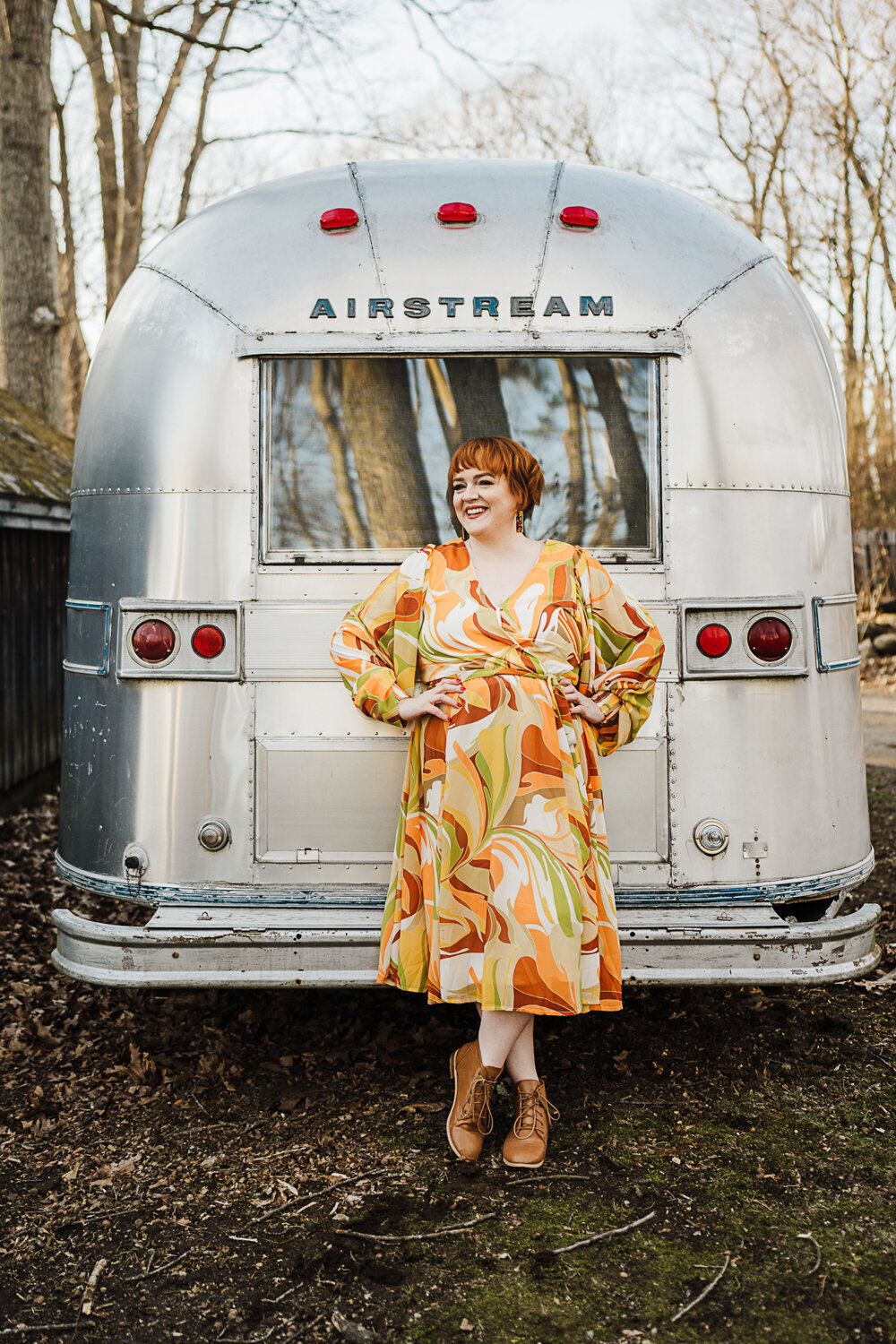 woman in 70s print dress does photoshoot with airstream