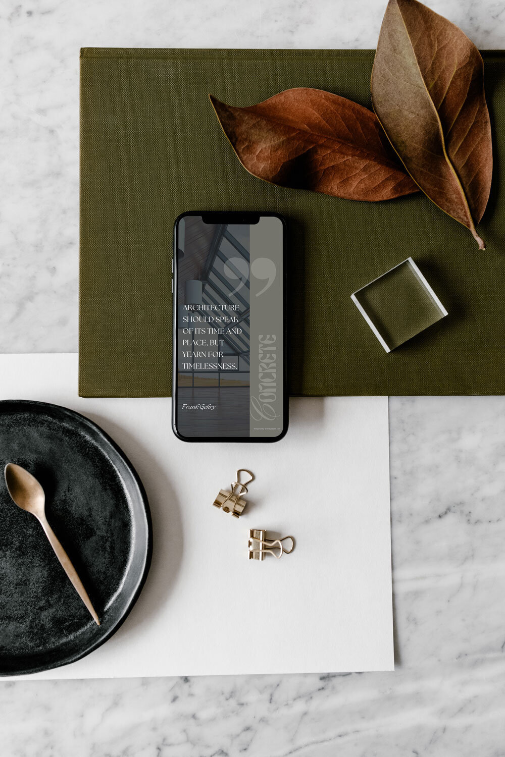 iphone with an image of concrete social media templates design for ease and steady launch sitting next to orange leaves on a green canvas cloth.
