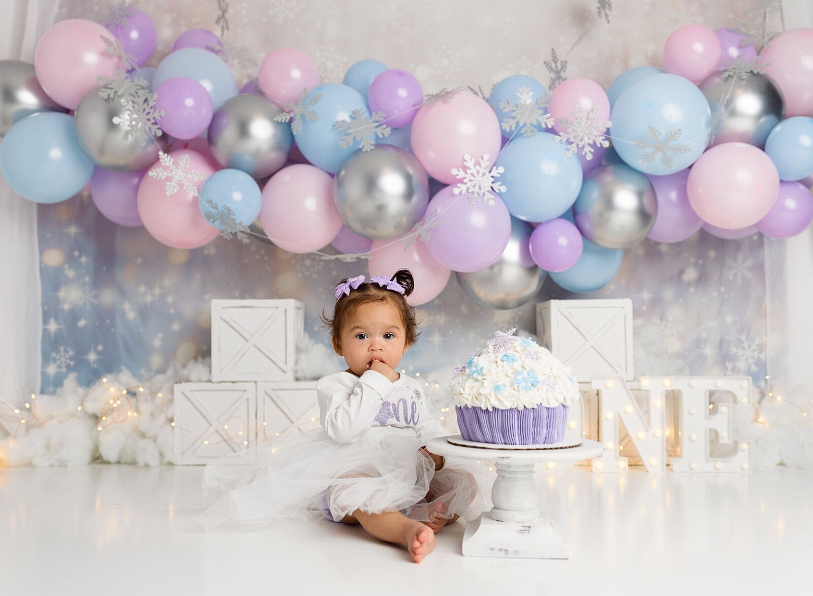 Little girl eating cake with a pastel themed backdrop