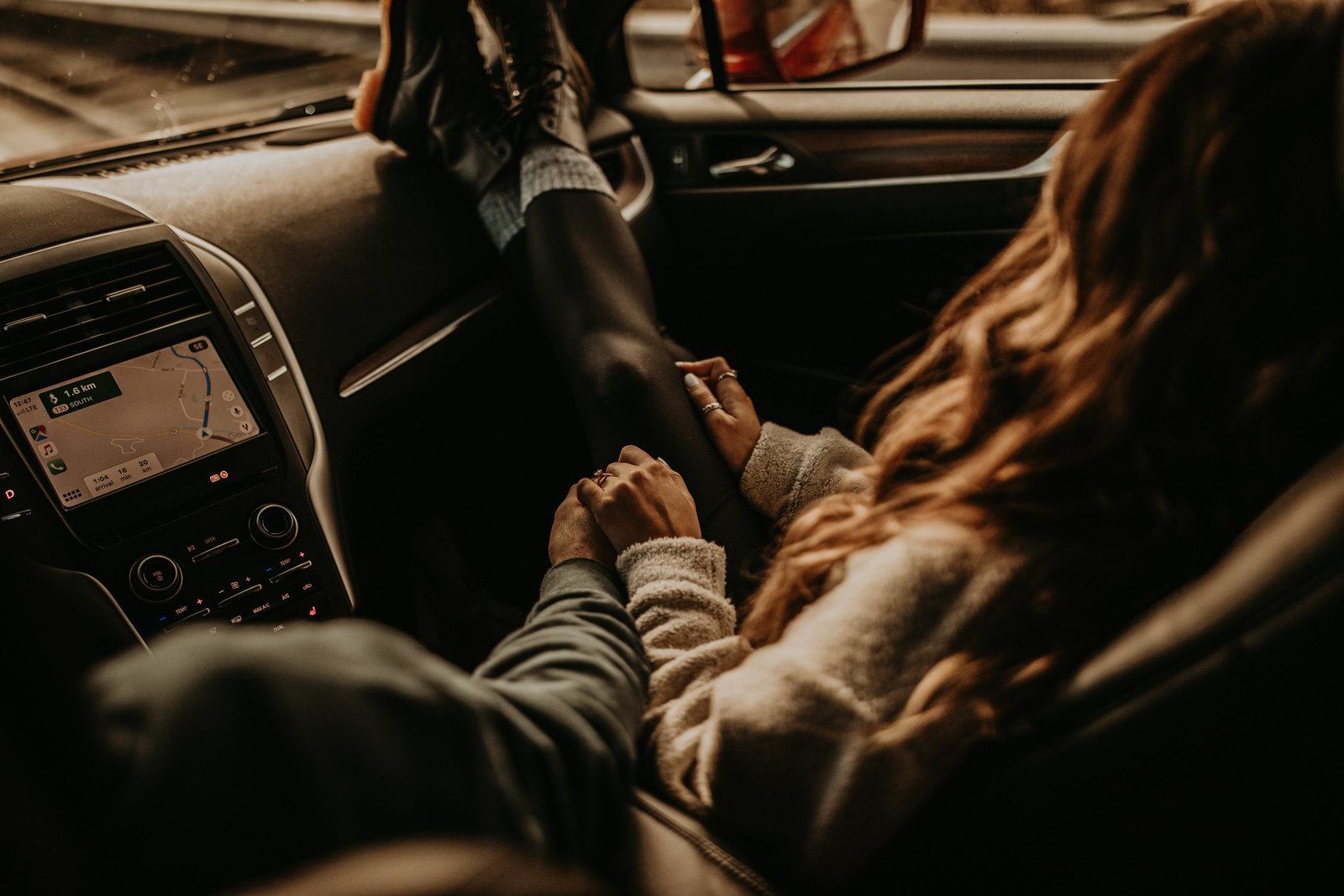 man and woman sitting in car holding hands