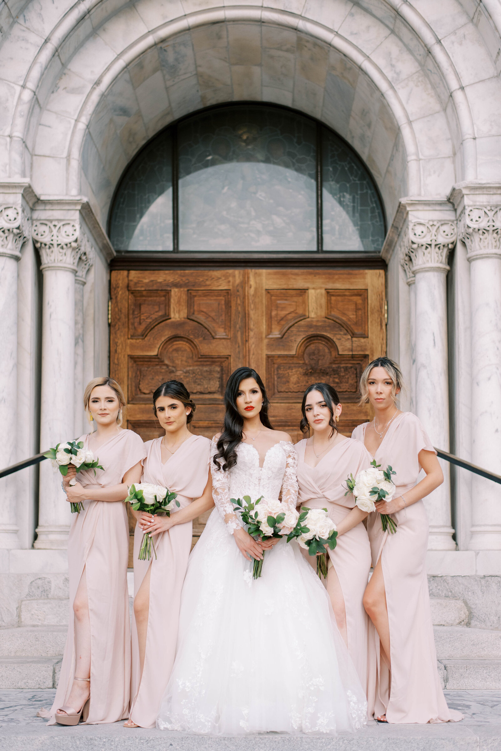 bride standing with bridesmaids on stairs on wedding day