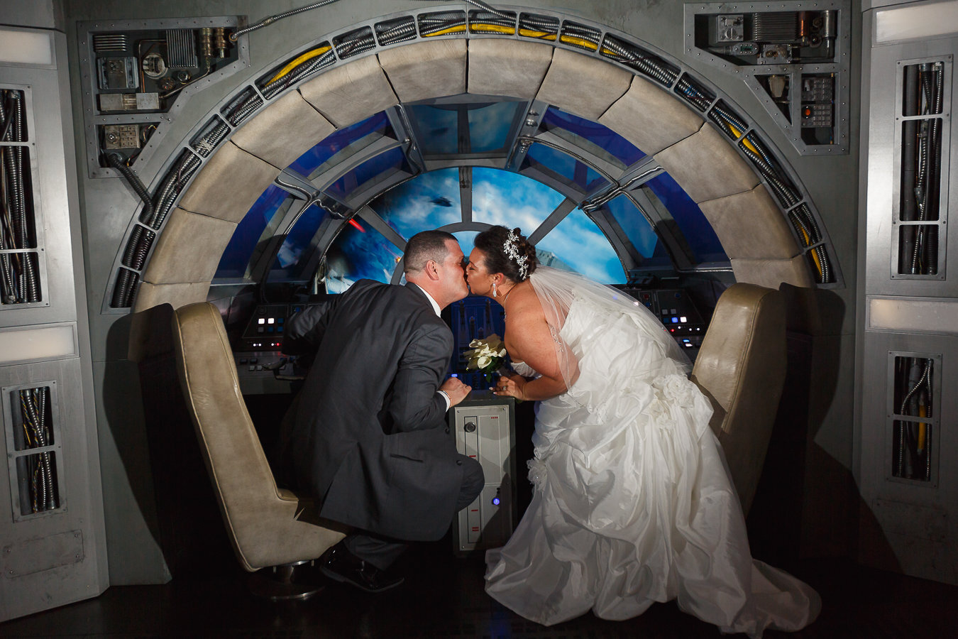 Bride and Groom kissing in front of the controls of the Millennium Falcon on Disney Wish Cruise Ship
