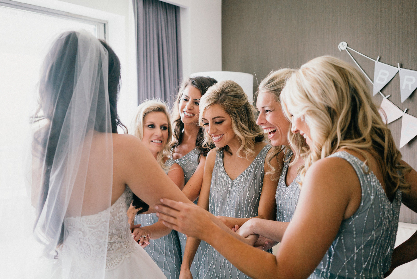 Bridesmaids gather around the bride and gush over her in her gorgeous gown.