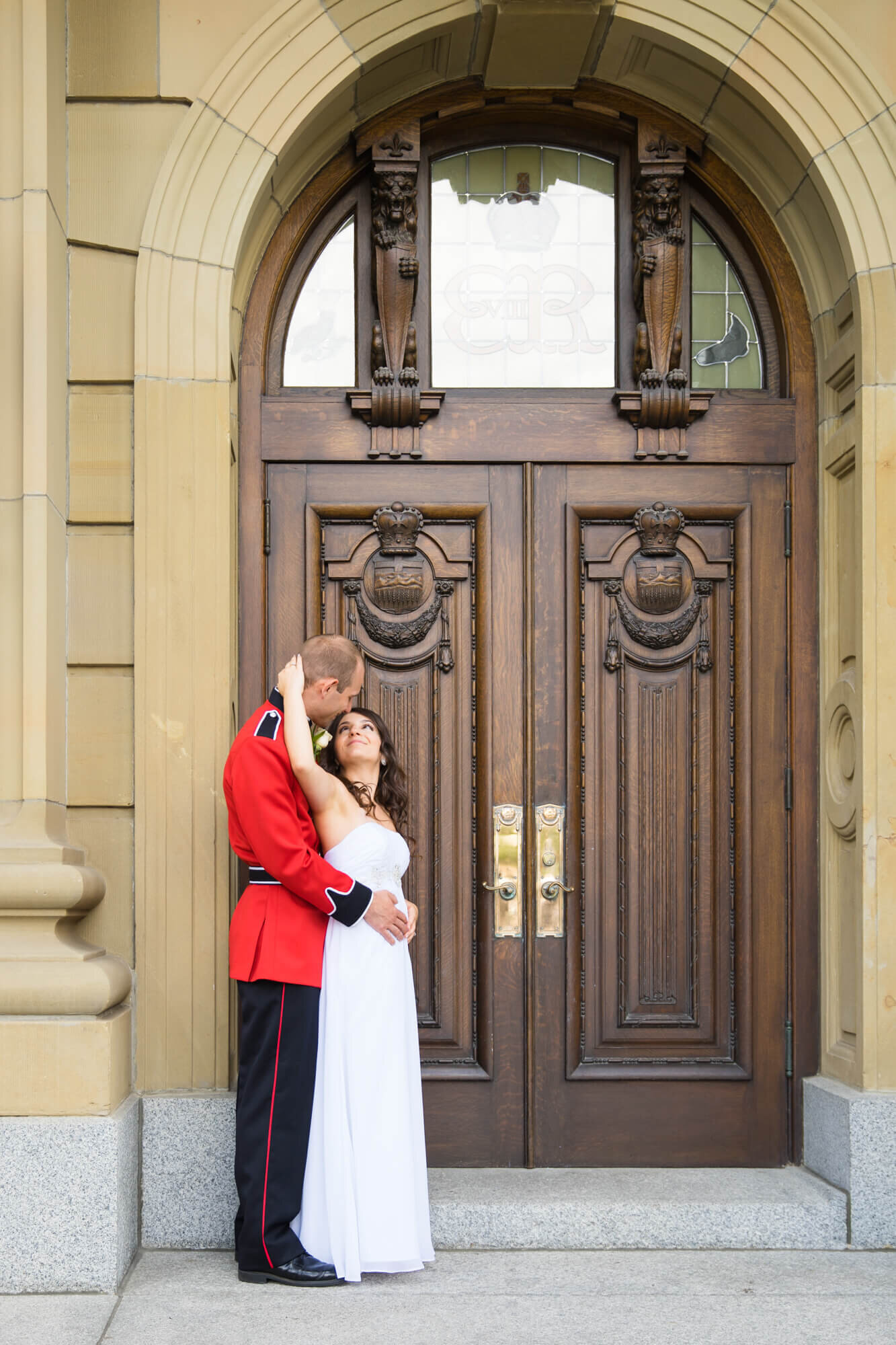 Bride reaching back, gently pulling RCMP groom;s head for a kiss