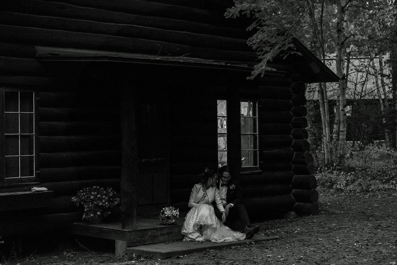 married couple sitting in front of their cabin at dusk
