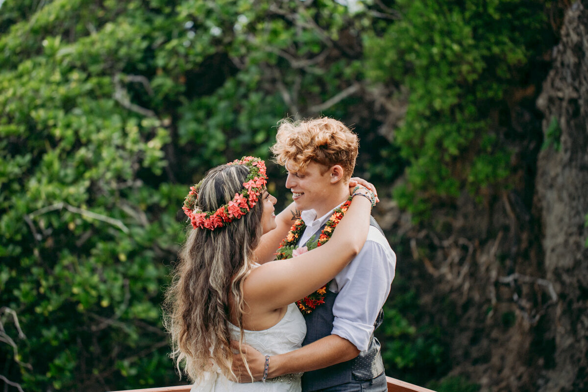 bride and groom kissing with green jungle behind them