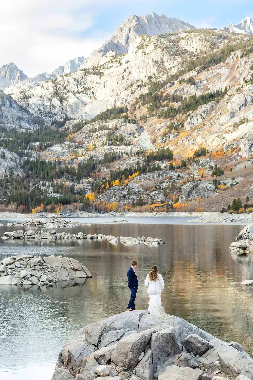 A bride and groom enjoy their wedding day in front of a pristine alpine lake in the Eastern Sierras at sunrise.