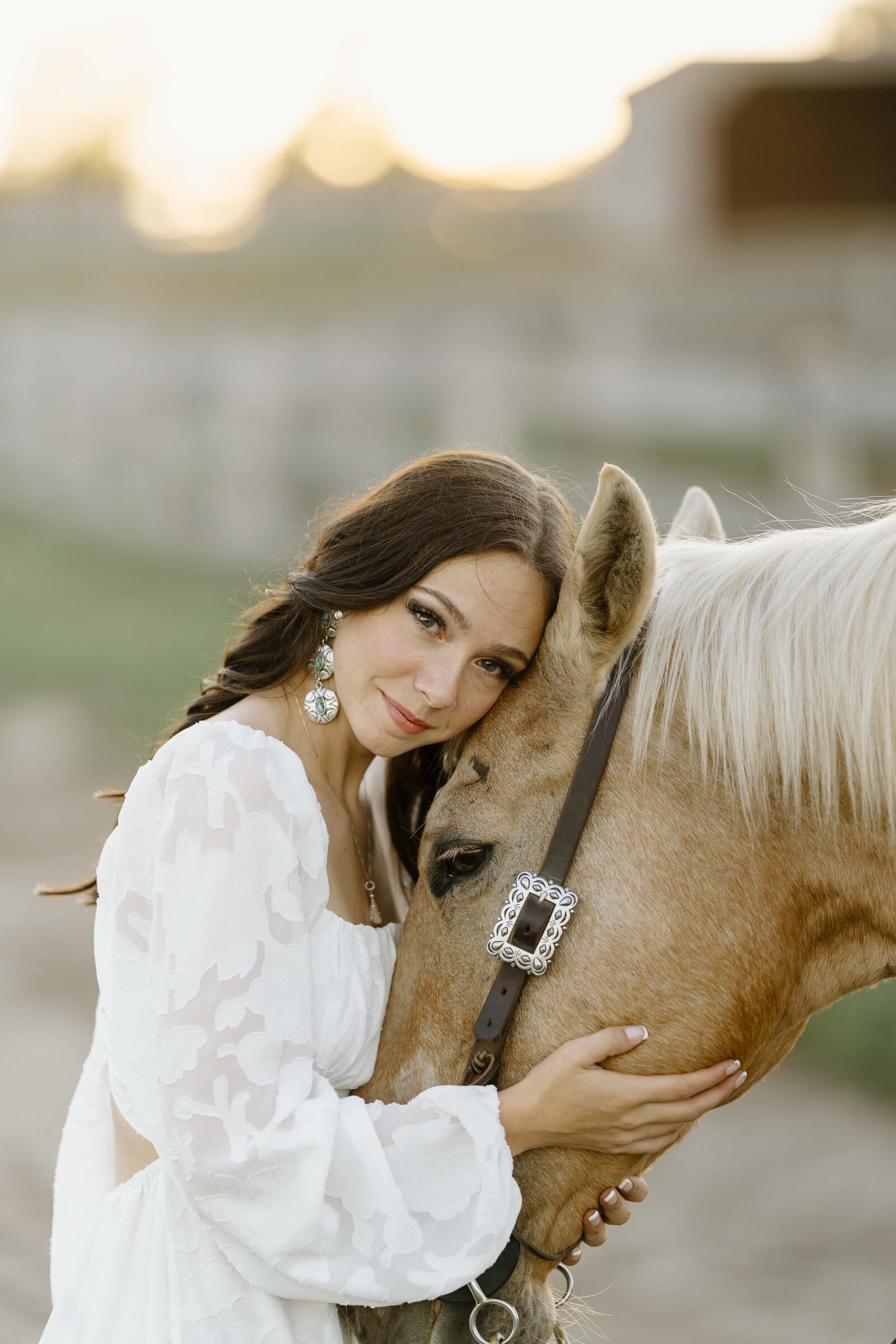 a girl in a white dress resting her head on her palomino horse's head