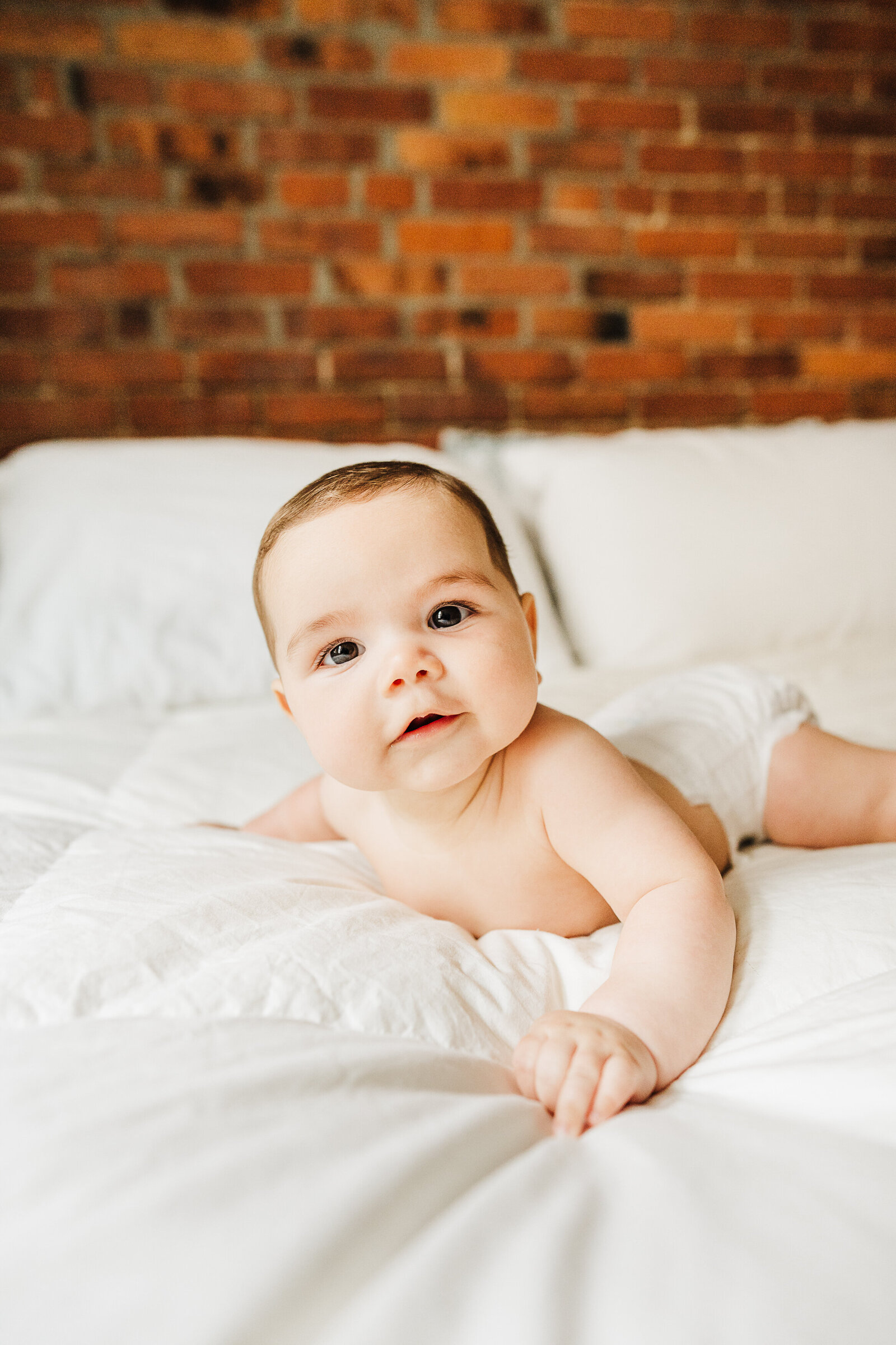 baby in a diaper looks at camera on bed