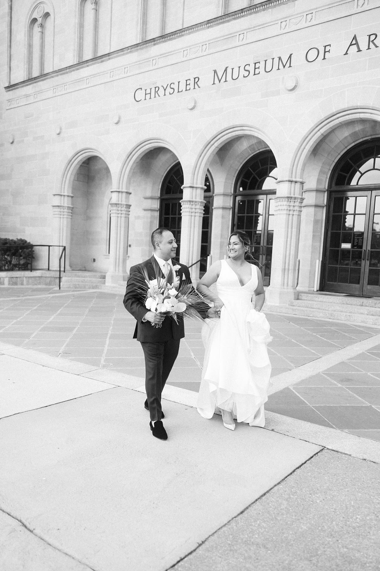 Black and White Photo of a couple walking together in front of the Chrysler Museum in Norfolk after their wedding ceremony by Virginia Beach Wedding photographer Mary Eleanor Photography