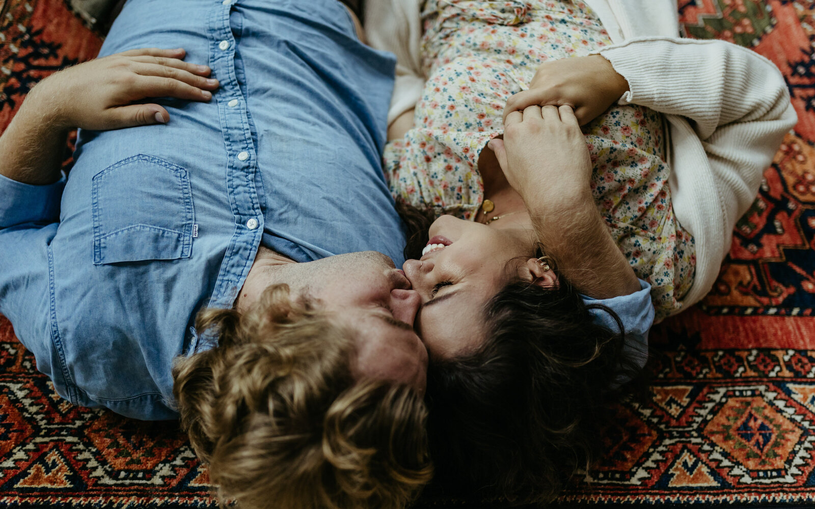 A man and woman lay on the floor while kissing
