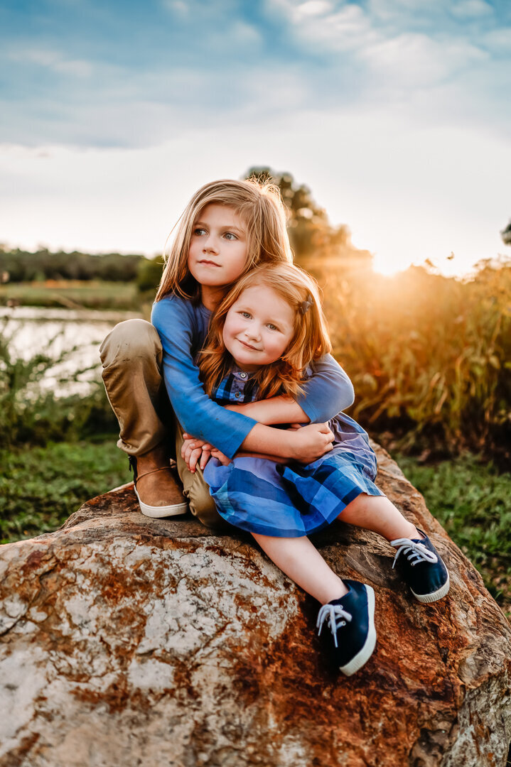 brother hugging sister on a rock