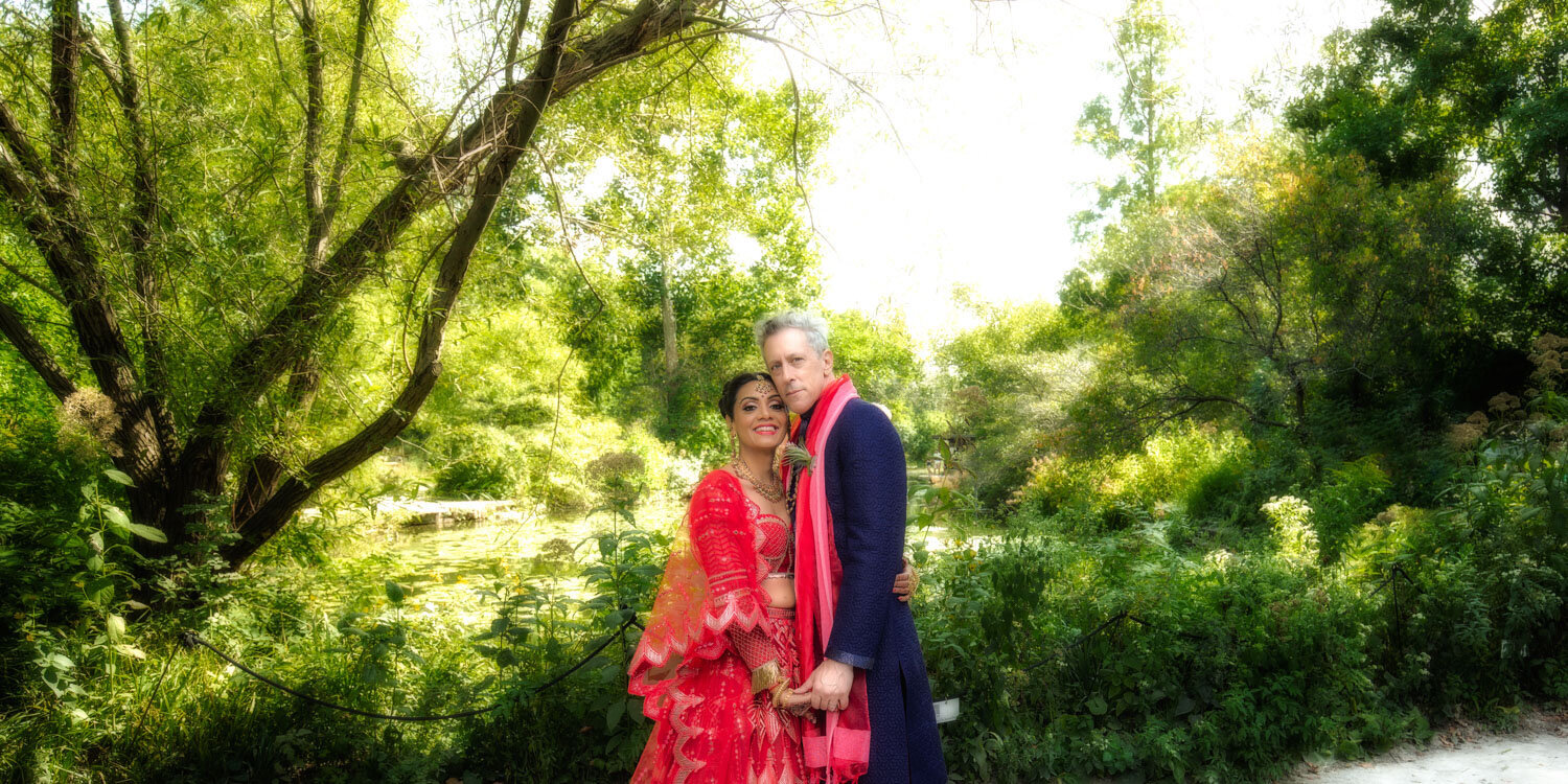 A bride and groom are posing for a picture in a park.