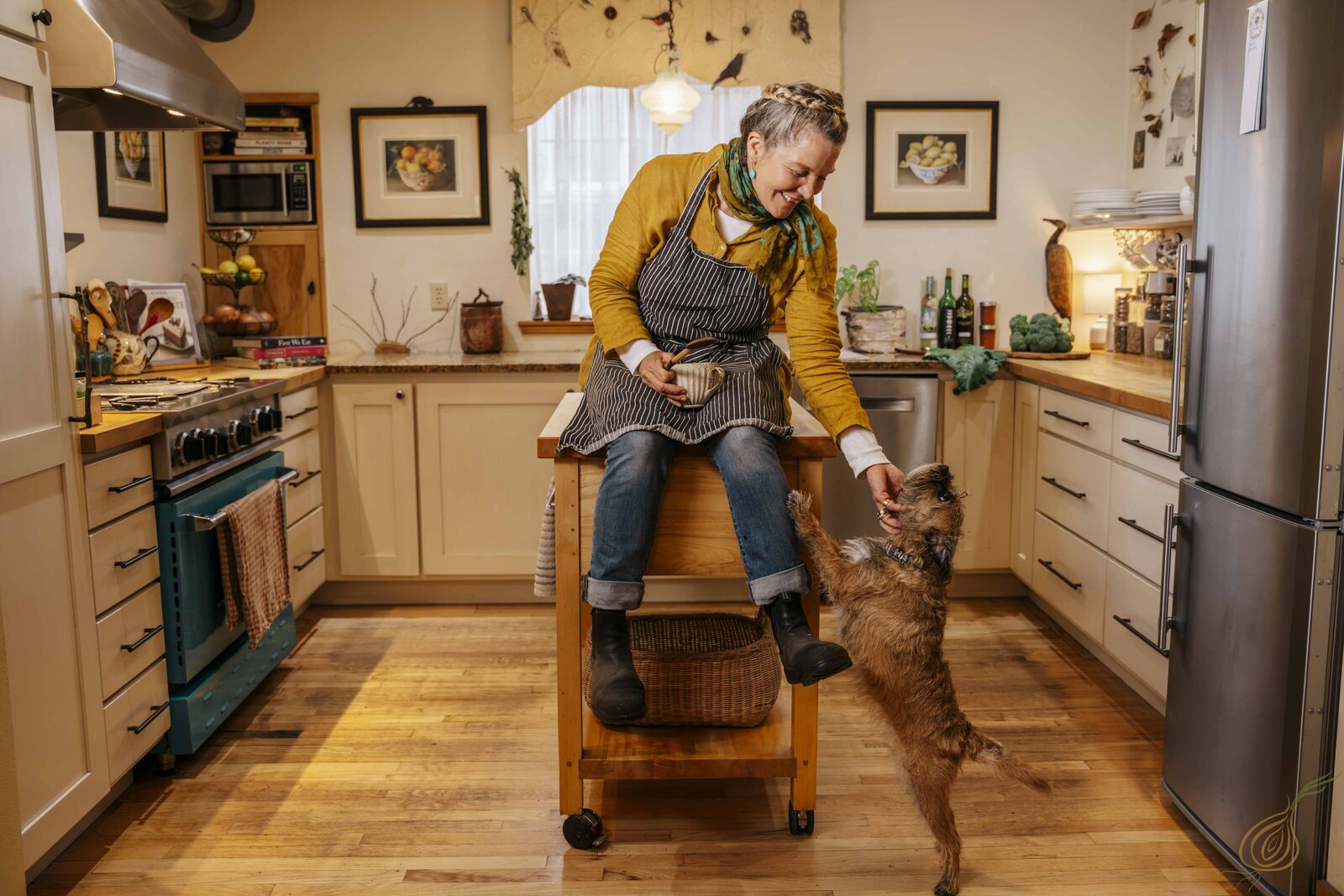 A woman sits on a kitchen island, smiling at her dog, creating a warm and inviting home atmosphere.