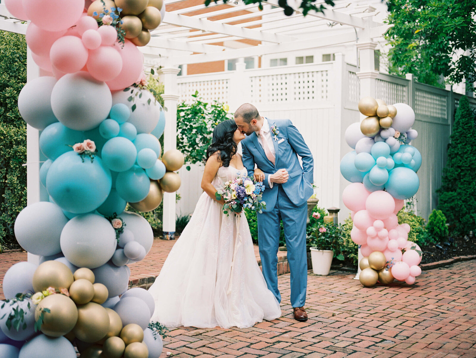 bride and groom kissing at elopement with balloons