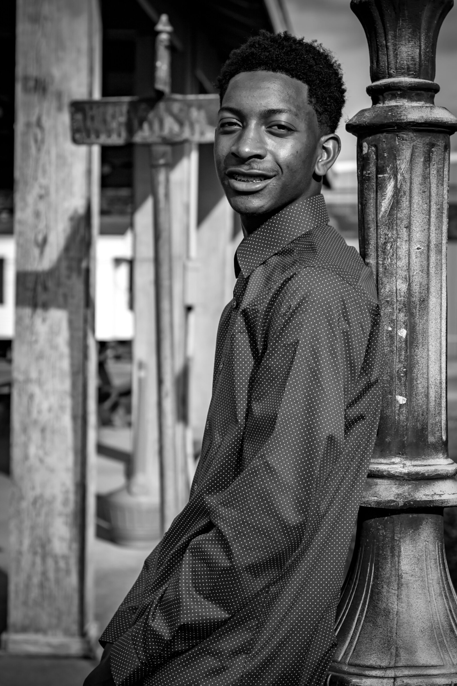 black and white photo with guy leaning against light post smiling