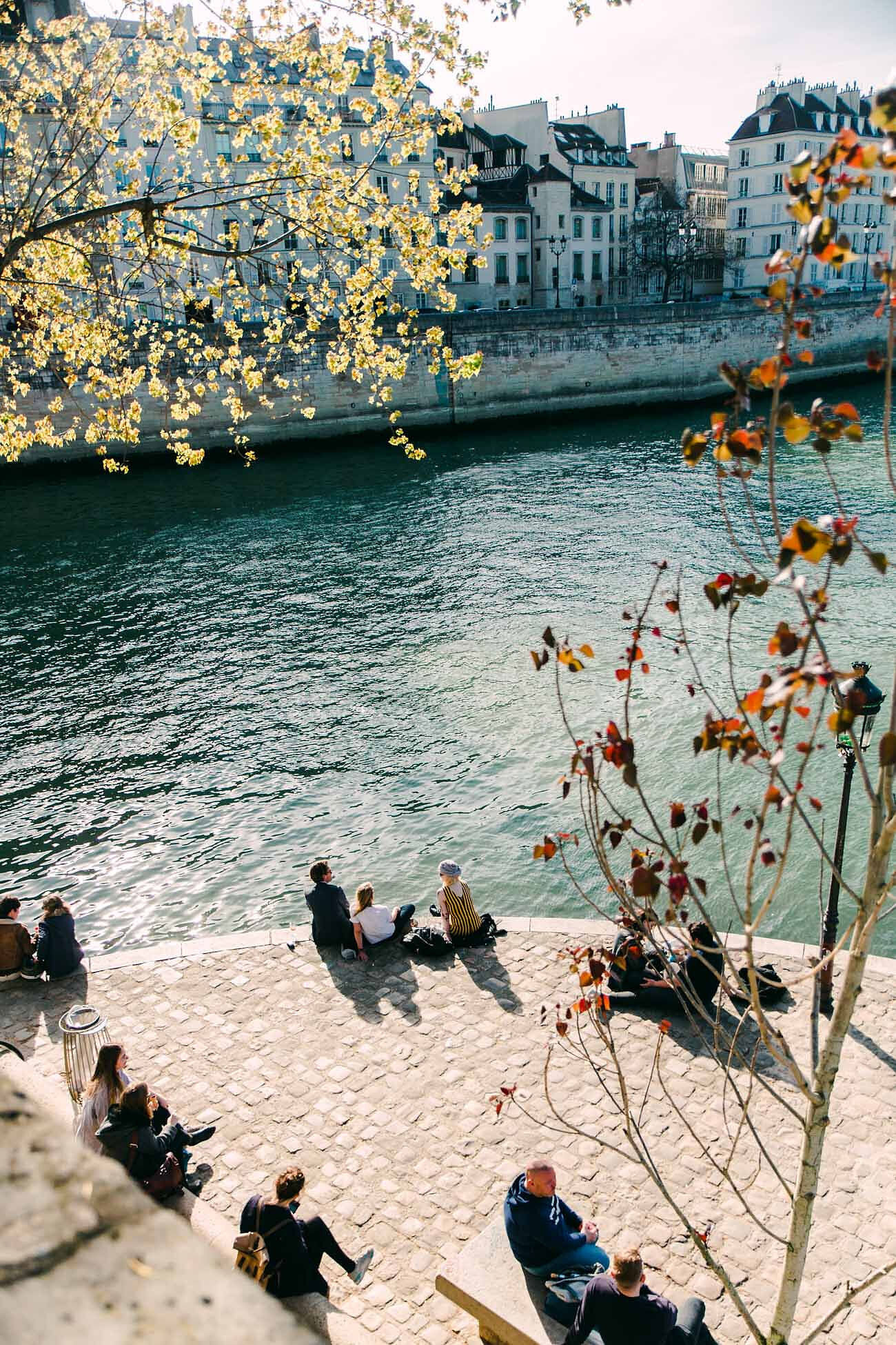 Chelsea Loren travel photographer capturing couples, people, scattered on the banks of the Seine having picnic in spring.