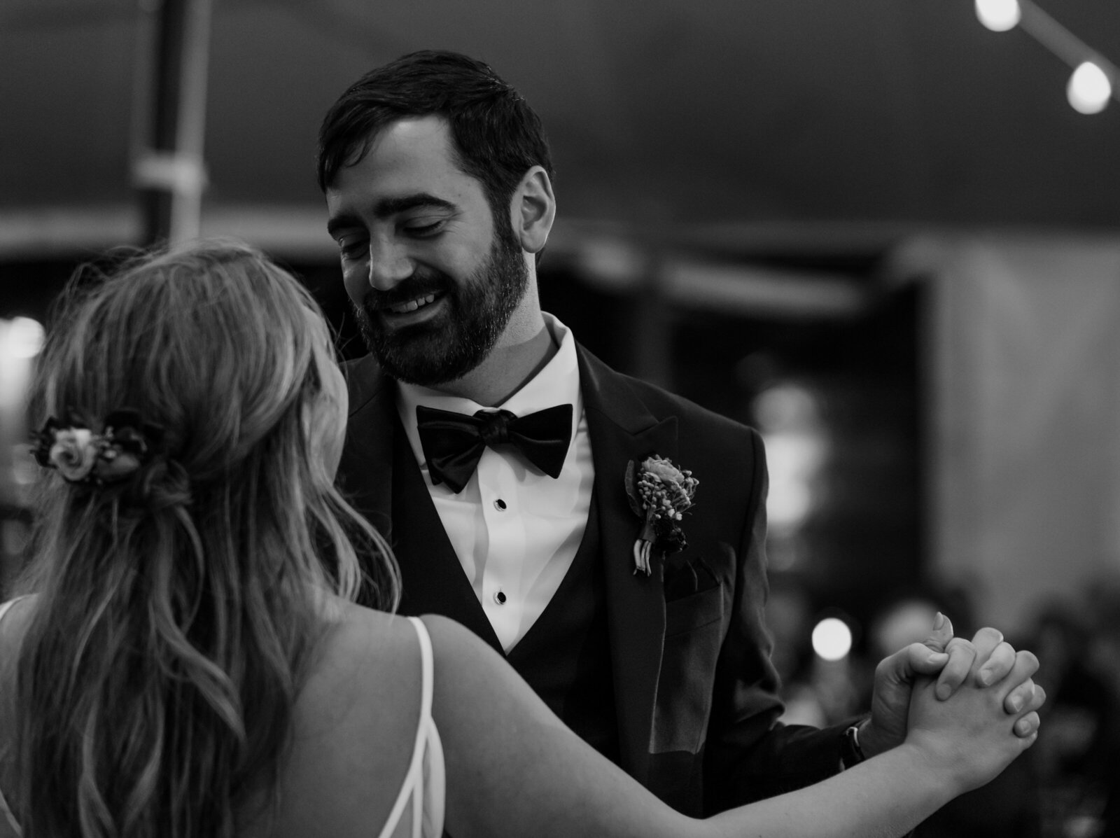 A bride and groom smile at each other while dancing at a reception