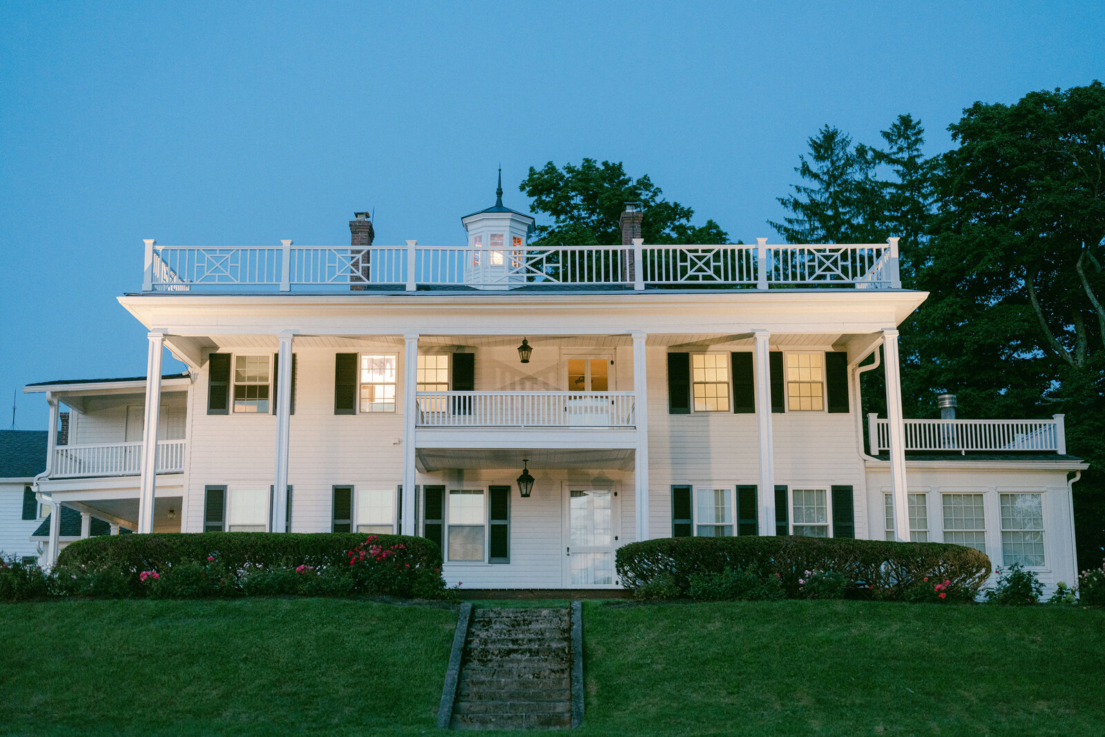 historic white home on estate at dusk with uplighting at Windridge