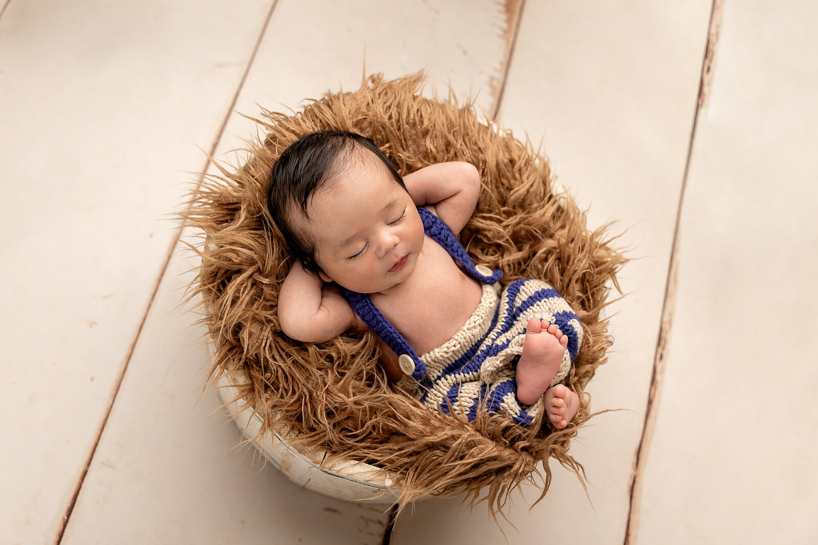 baby in suspenders sleeping in bowl by Newborn Photography Bucks County PA