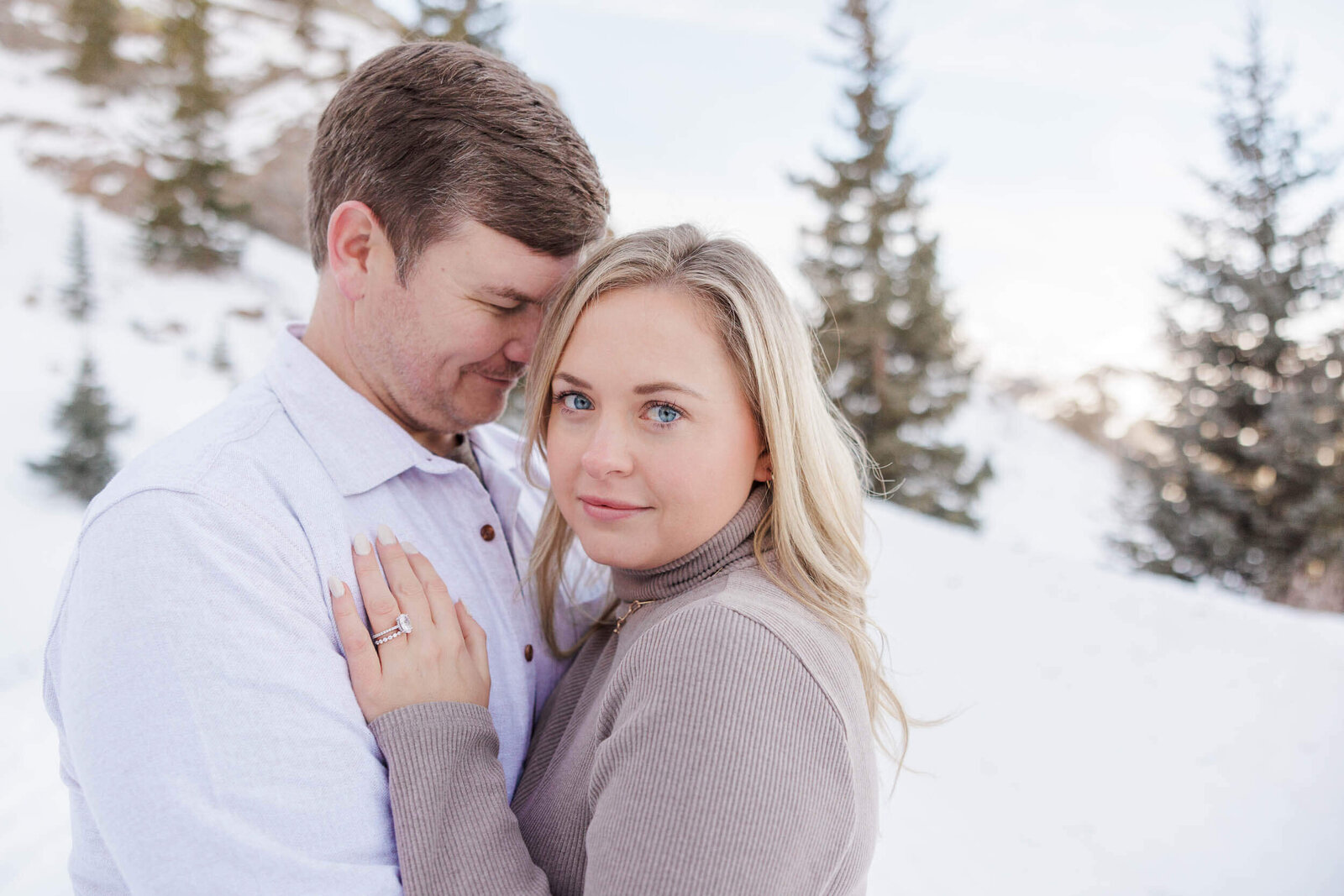 A husband and wife are cuddled close together on a cold winter morning as posed by their Breckenridge Photographer