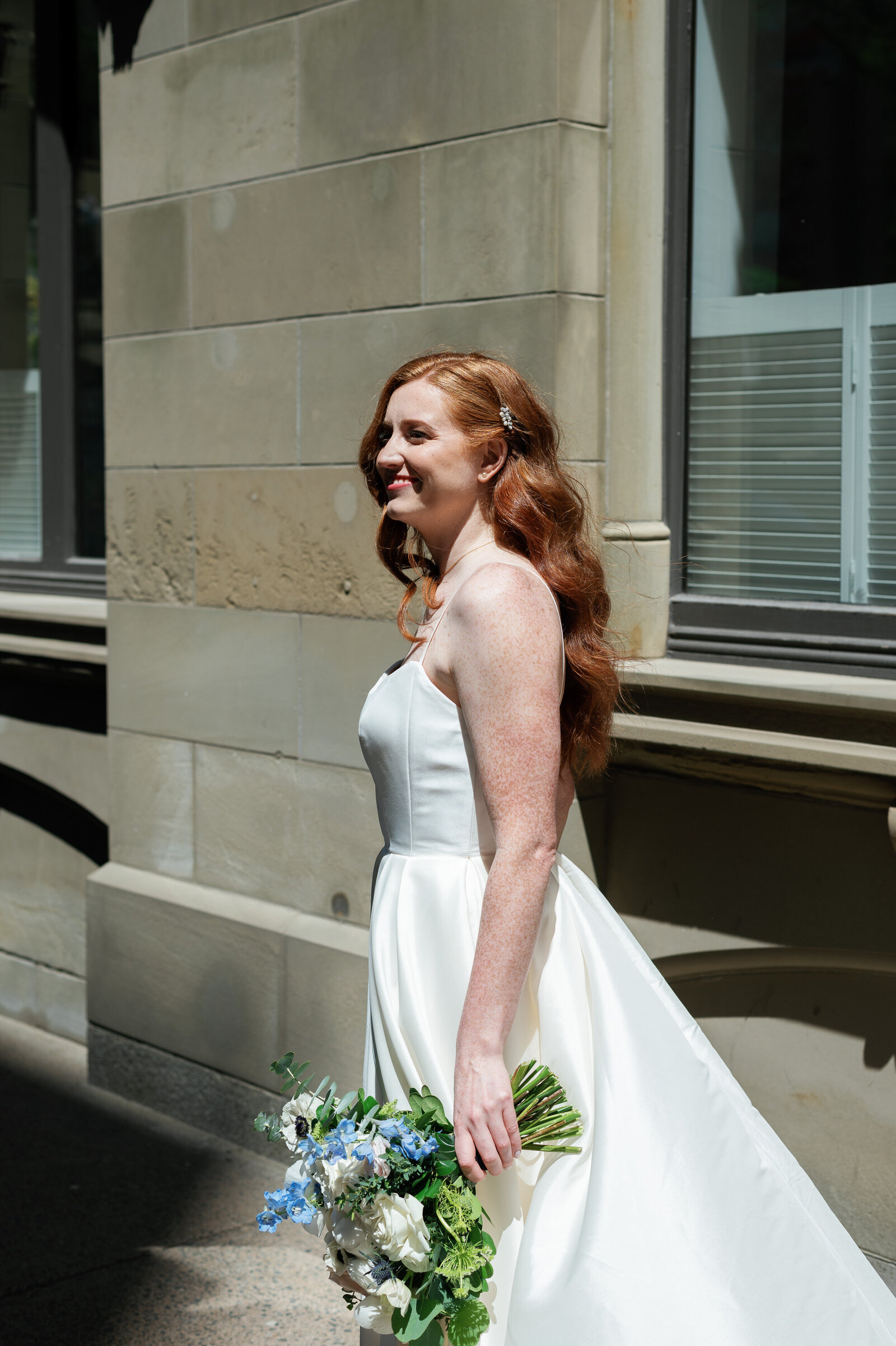 Smiling bride holding flowers on a sunny day downtown Halifax.