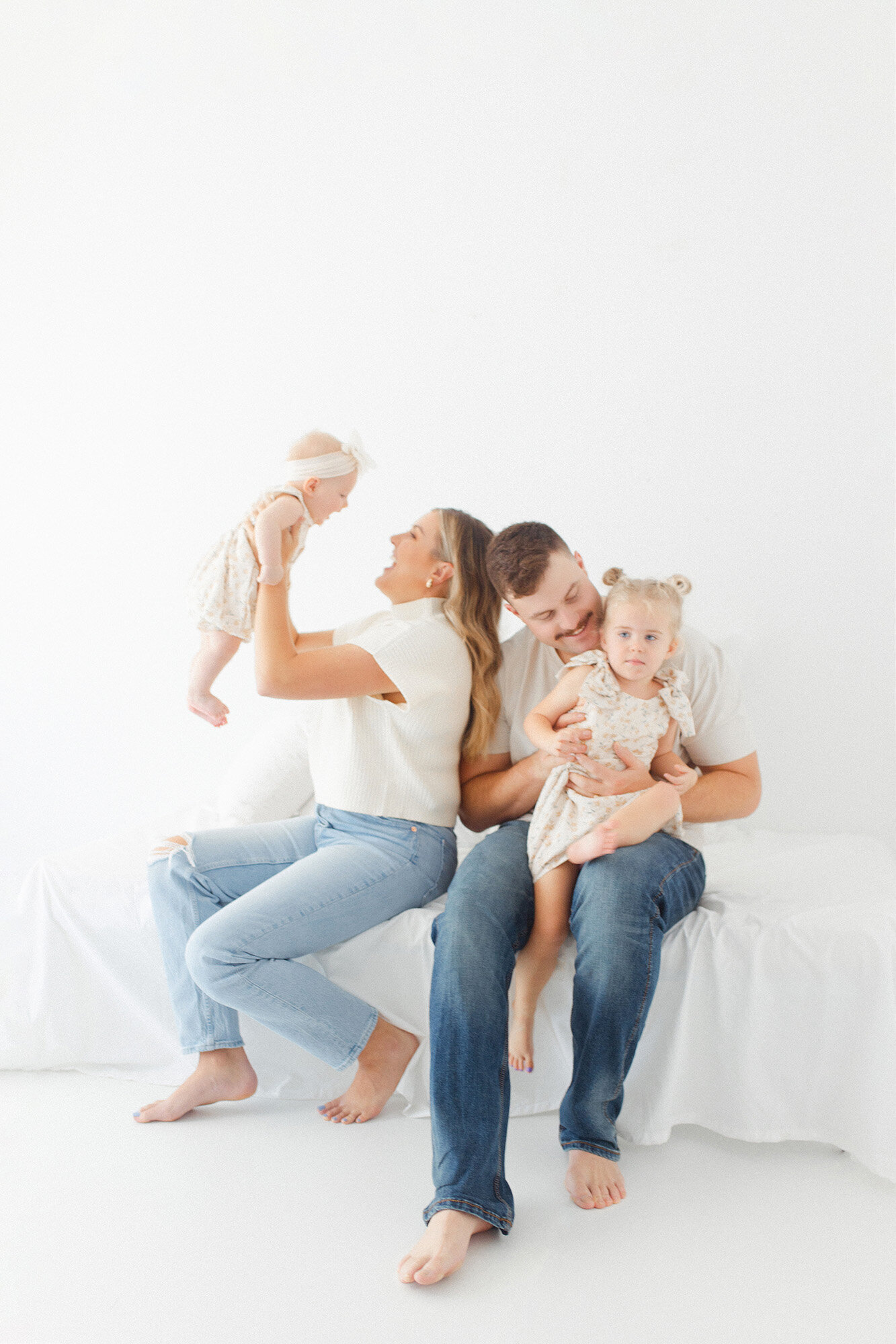 A lifestyle photo of a mom and dad playing with their young kids during their session in Grand Forks