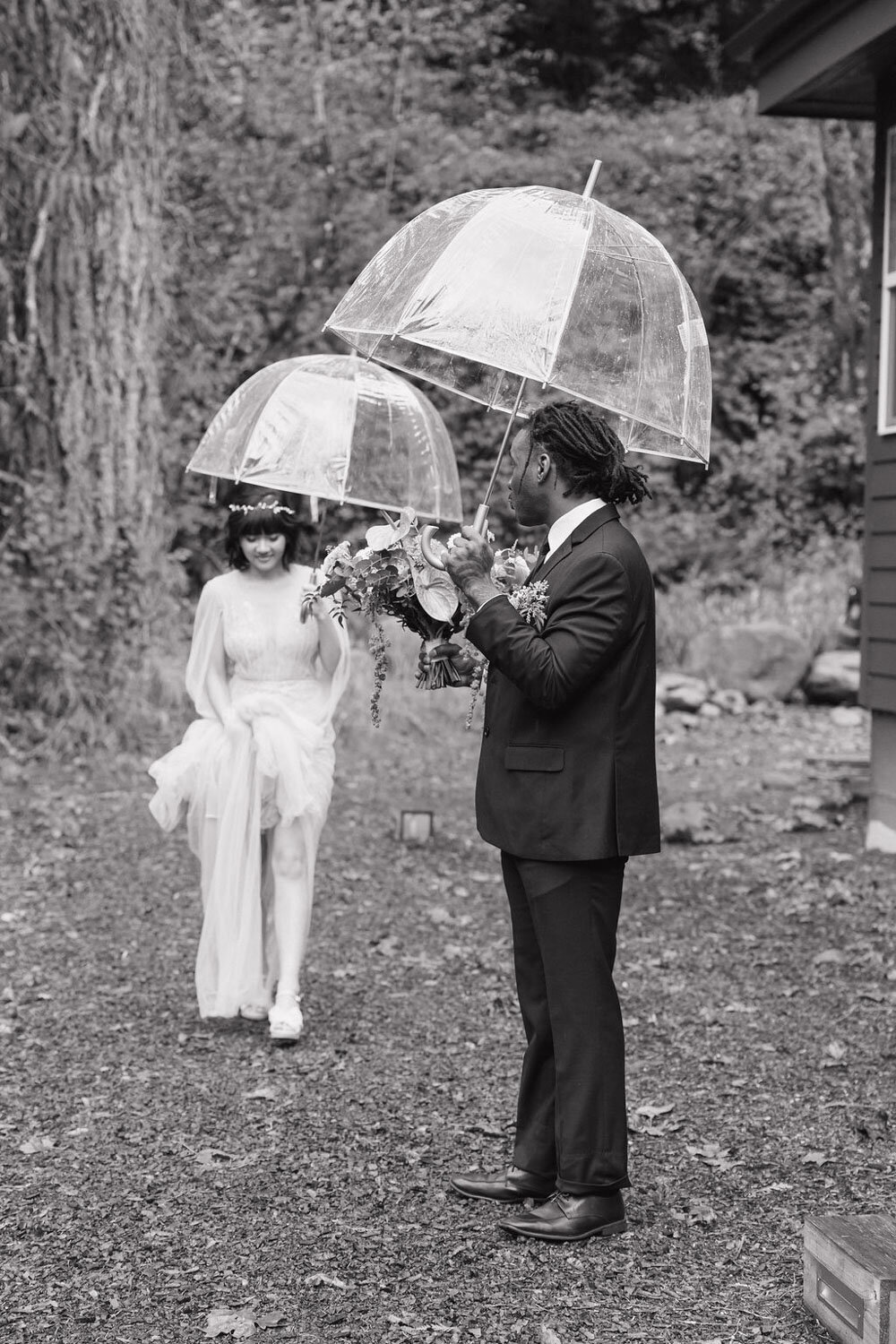 black and white photo of bride and groom holding their clear umbrella