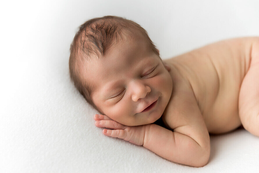 Newborn baby smiles for his photography session.