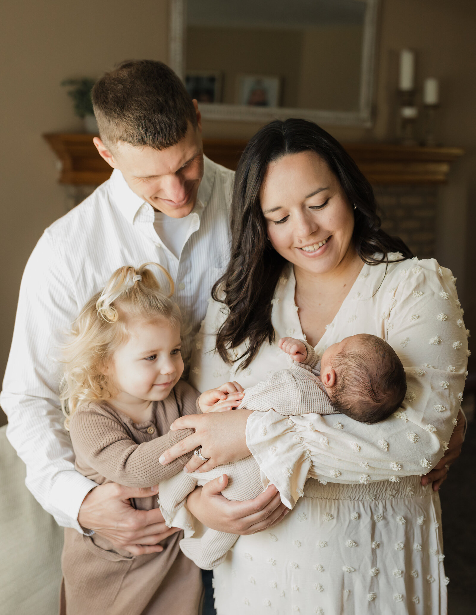 mom, dad, sister holding newborn baby boy for in home lifestyle photoshoot