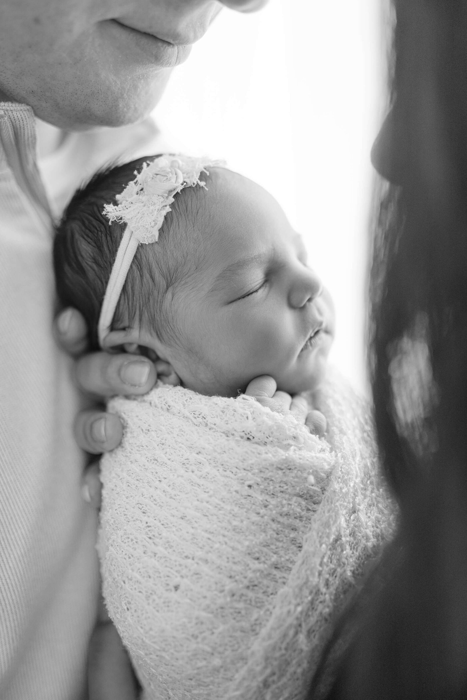 captivating black and white portrait of a newborn baby girl being snuggled by her mom and dad in their Wheeler District home