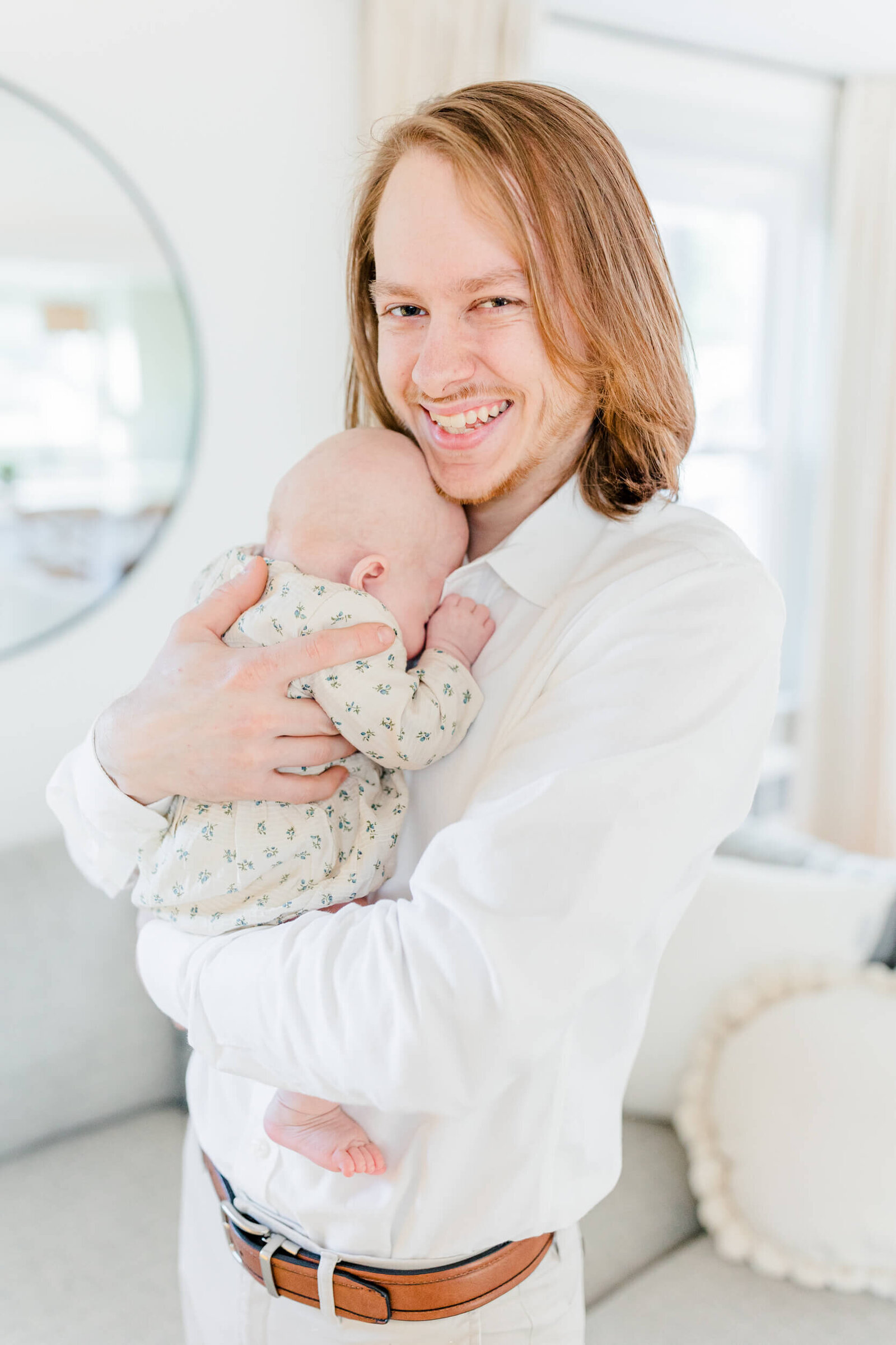 Dad smiles while newborn sleeps on his chest