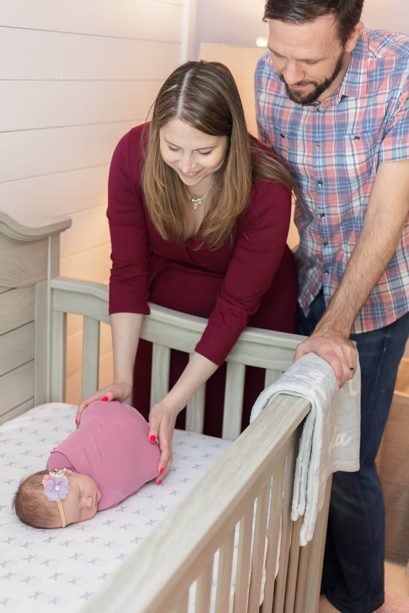 A Northern Virginia couple standing over their baby girl's crib and smiling.