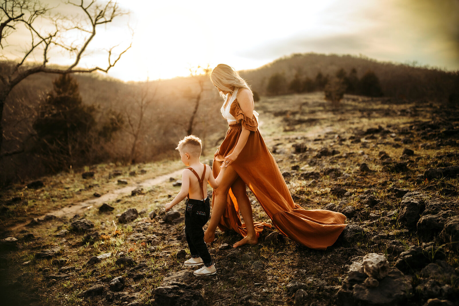 mother holds son hand as they walk through the hills