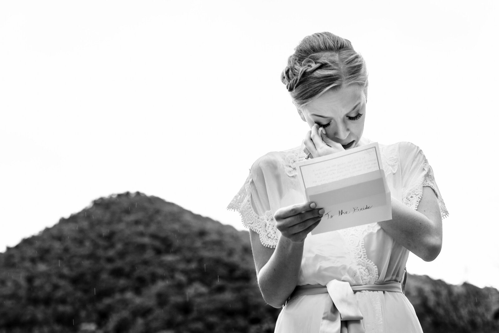 Bride wipes away a tear as she reads a letter from the groom