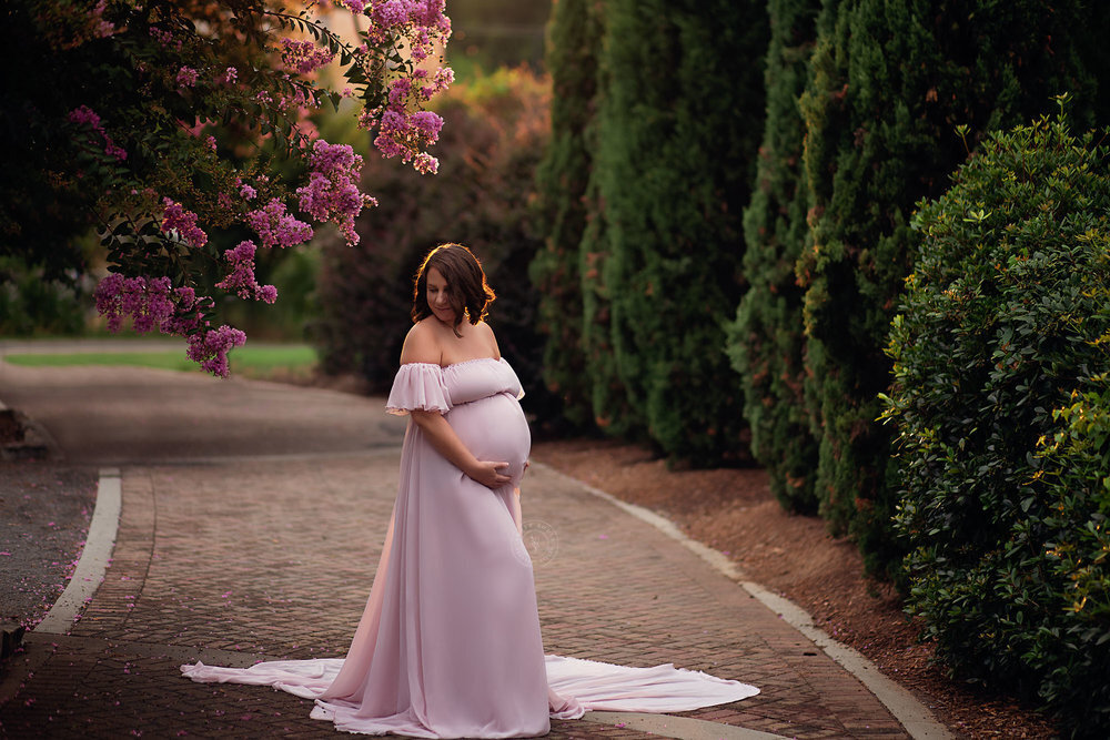 pregnant woman holding belly standing on path