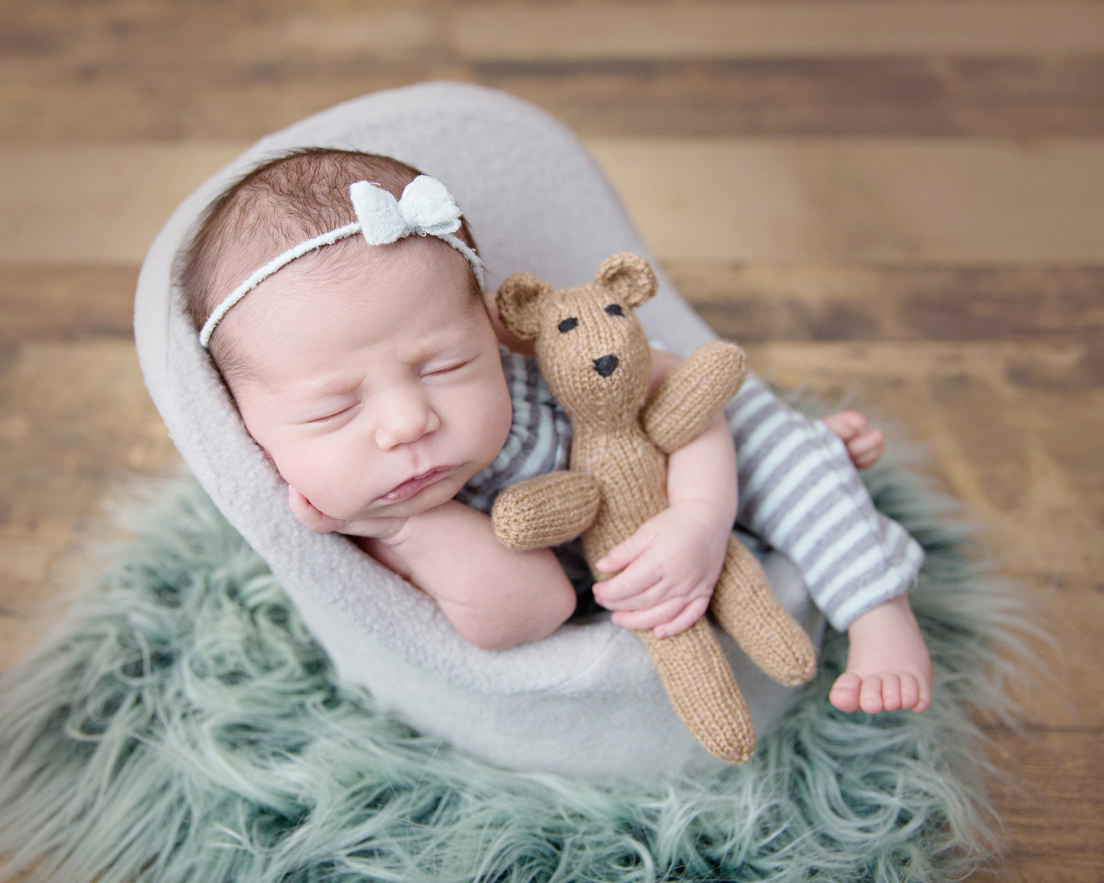 sleeping baby girl in posing pod with little teddy bear