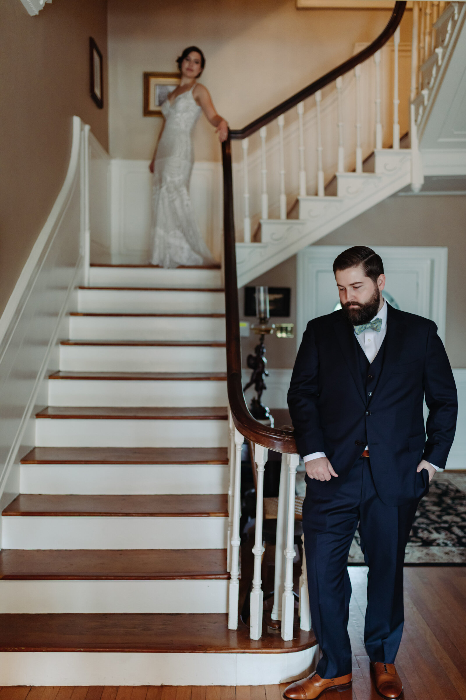 A bride stands at the top of a grand staircase with the groom at the bottom