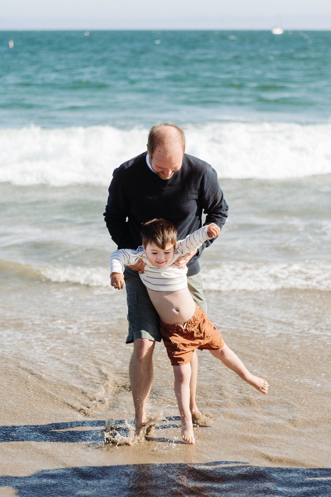 Father and son playing during family photo session at East Beach in Santa Barbara by Danielle Motif Photography