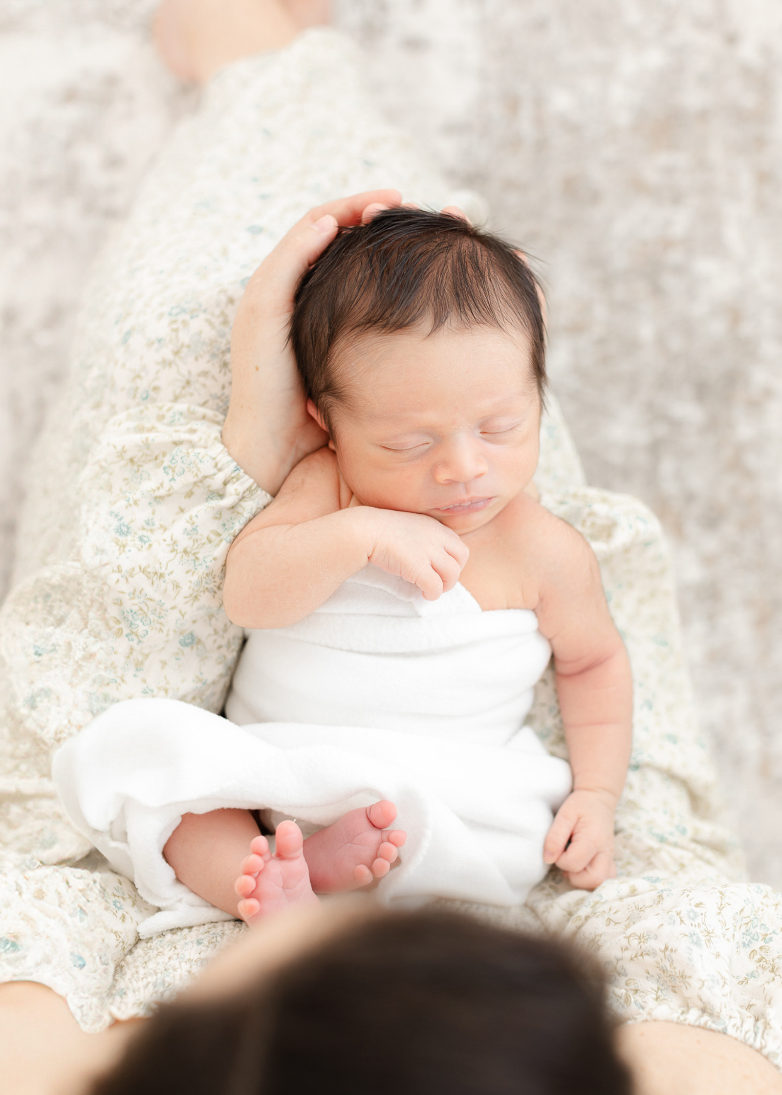 newborn baby sleeps in moms lap during newborn photoshoot