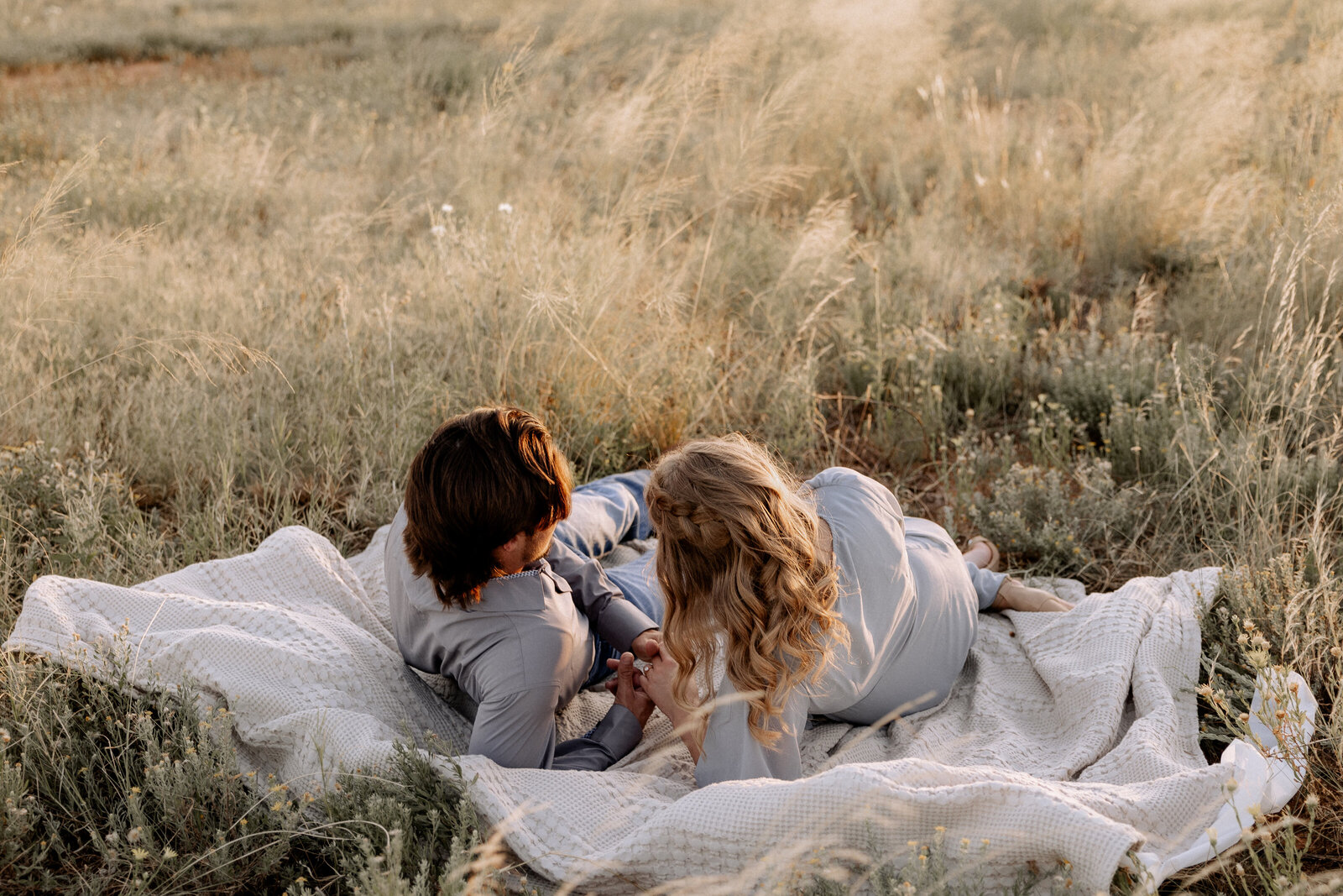 couple laying on picnic blanket in open field
