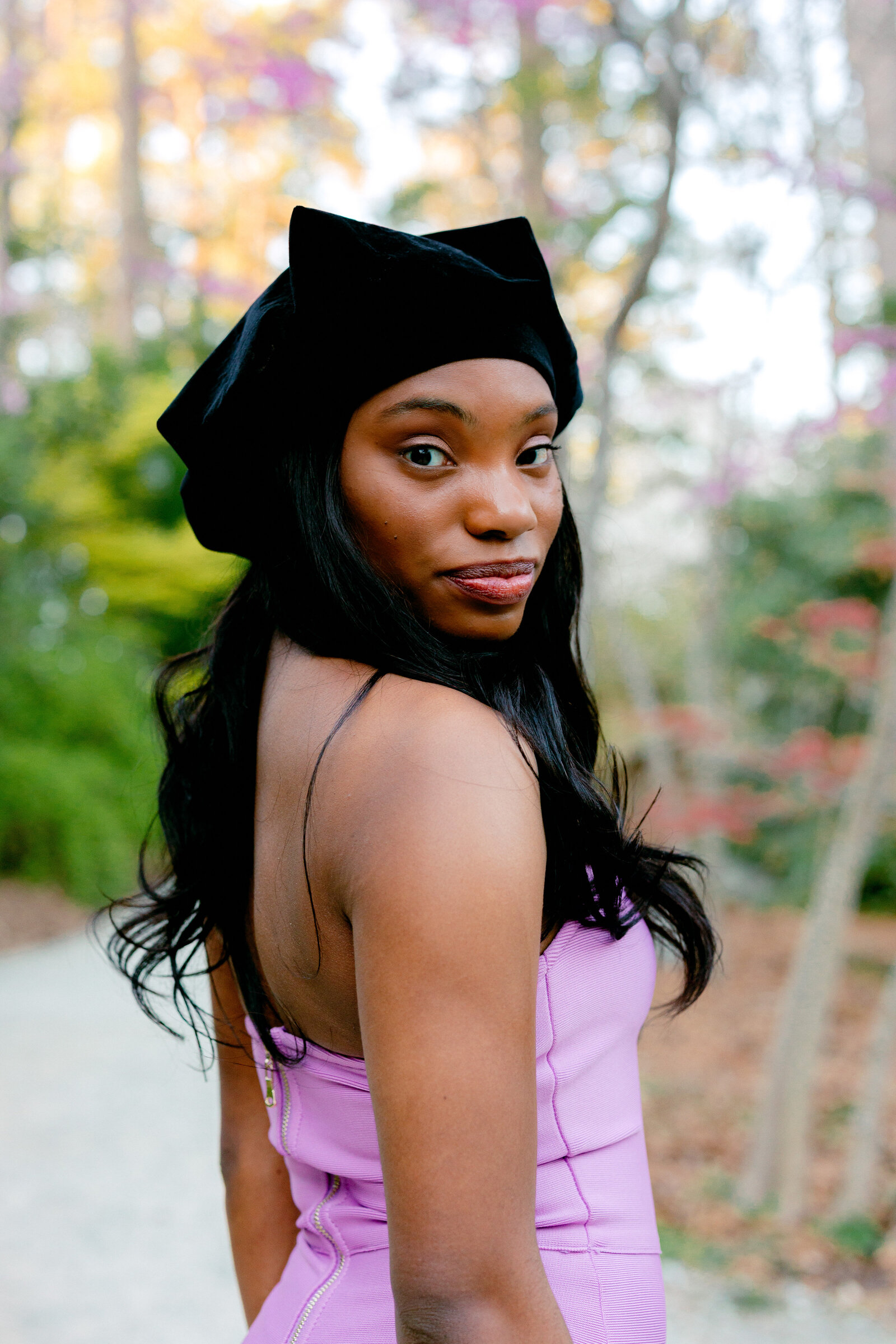 Duke doctorate graduate smiling over her shoulder for portraits at Duke Gardens.