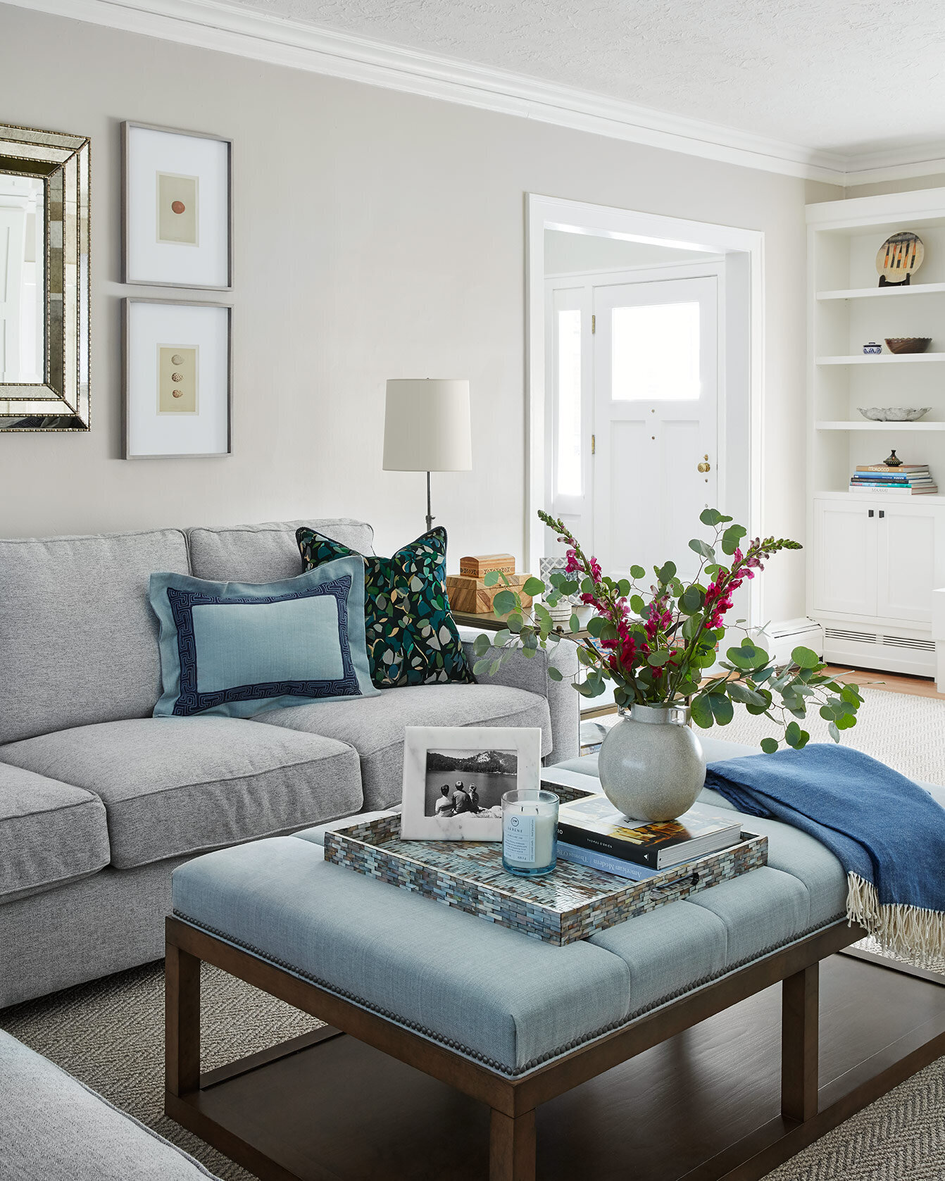 Modern living room design with a light grey couch and blue accents