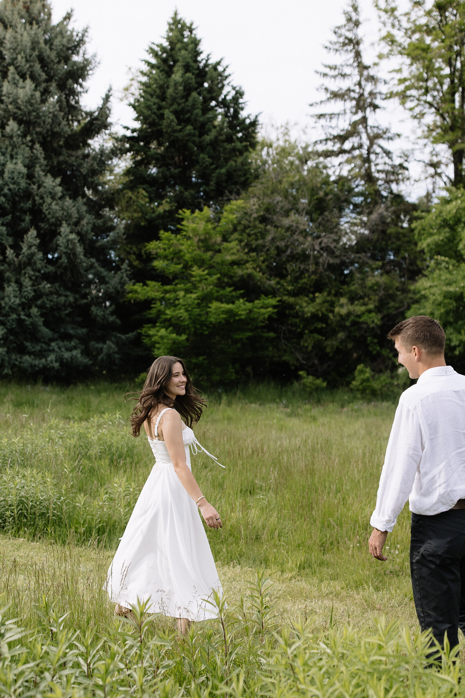 Couple walking through grassy meadow near downtown Coeur d'Alene after their elopement