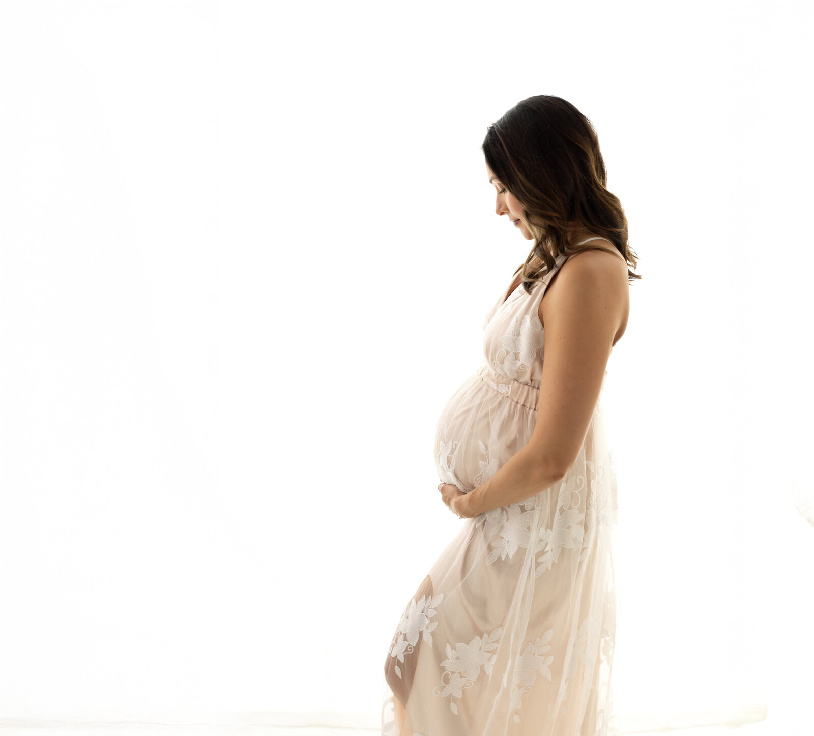 pregnant mother in cream maternity gown holding baby bump Cleveland family photographer