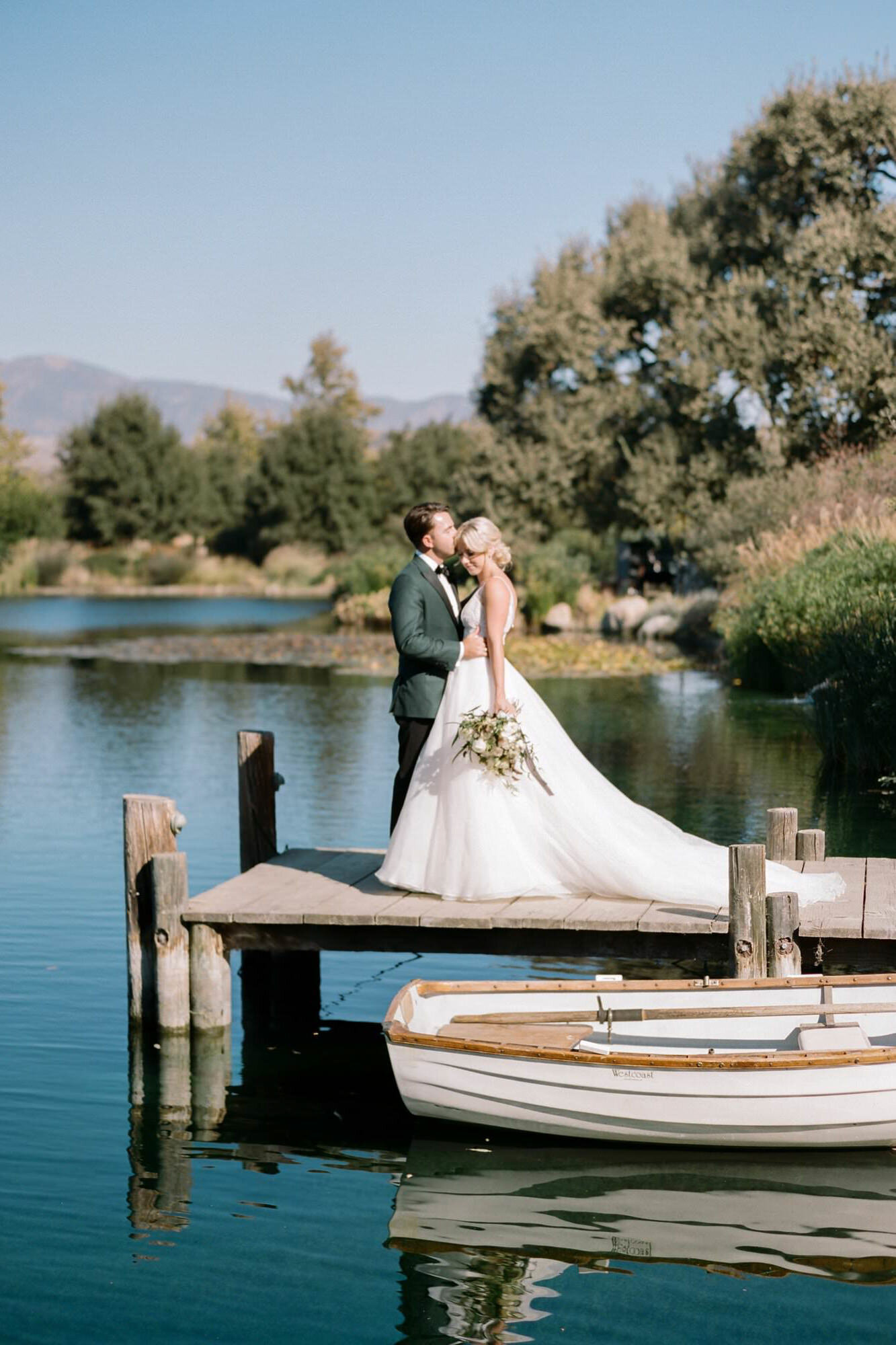 Bride and groom embrace on a dock on the water