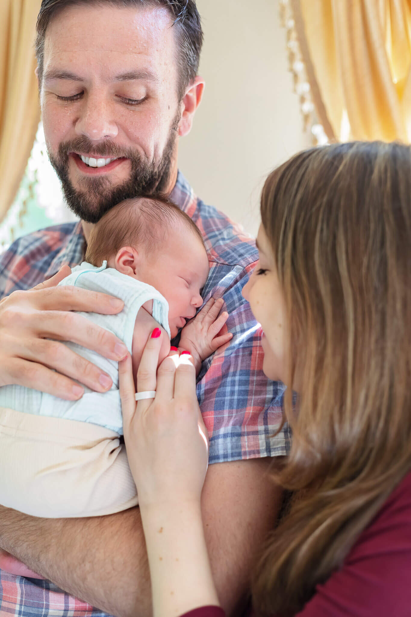 A close-up of mom snuggling in and smiling at the baby while dad holds her on his shoulder.