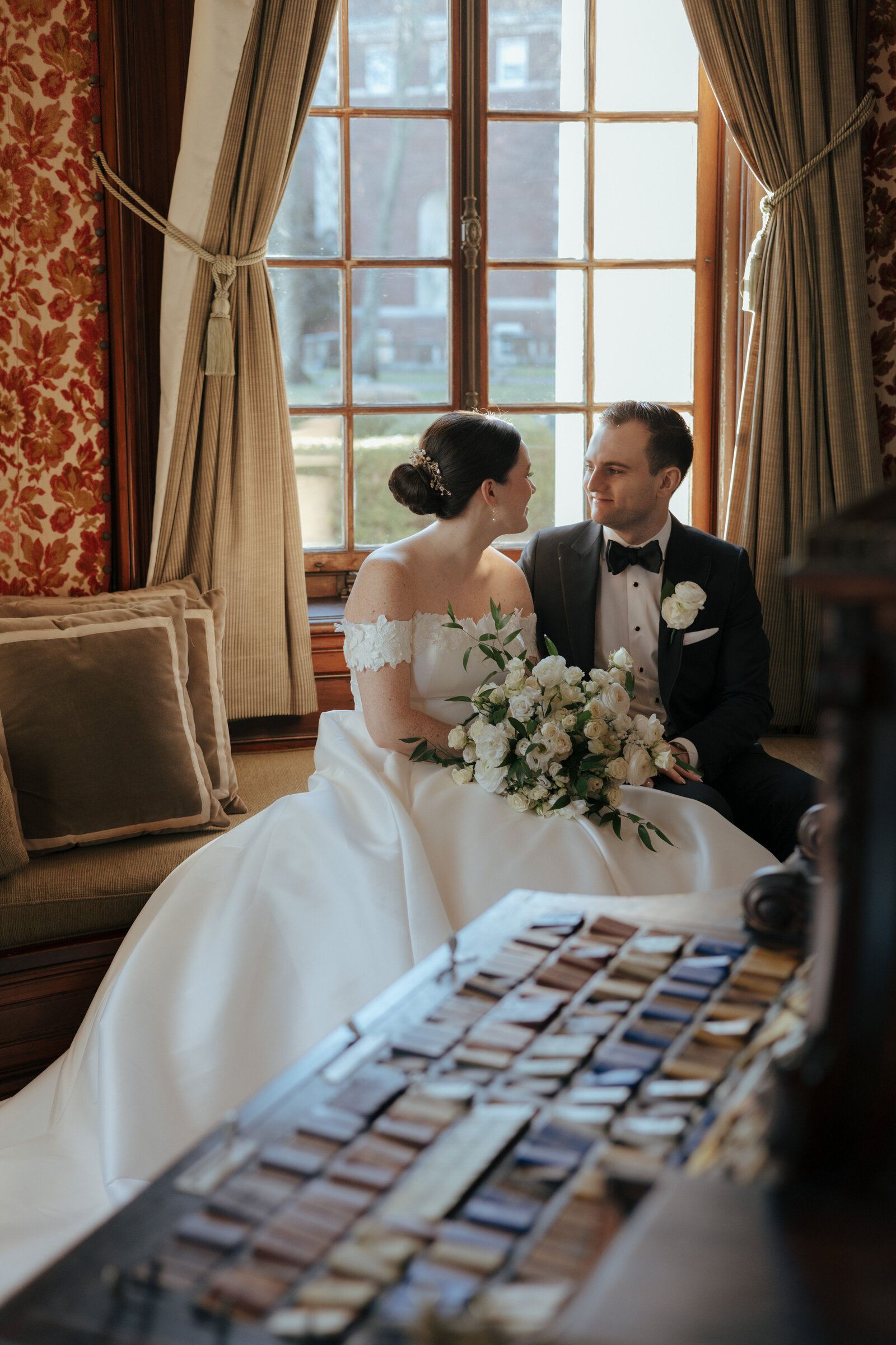 Bride and groom stare lovingly into each other's eyes at vintage wedding venue seated behind their table of matchbook favors | Emma LeeAnn Photography